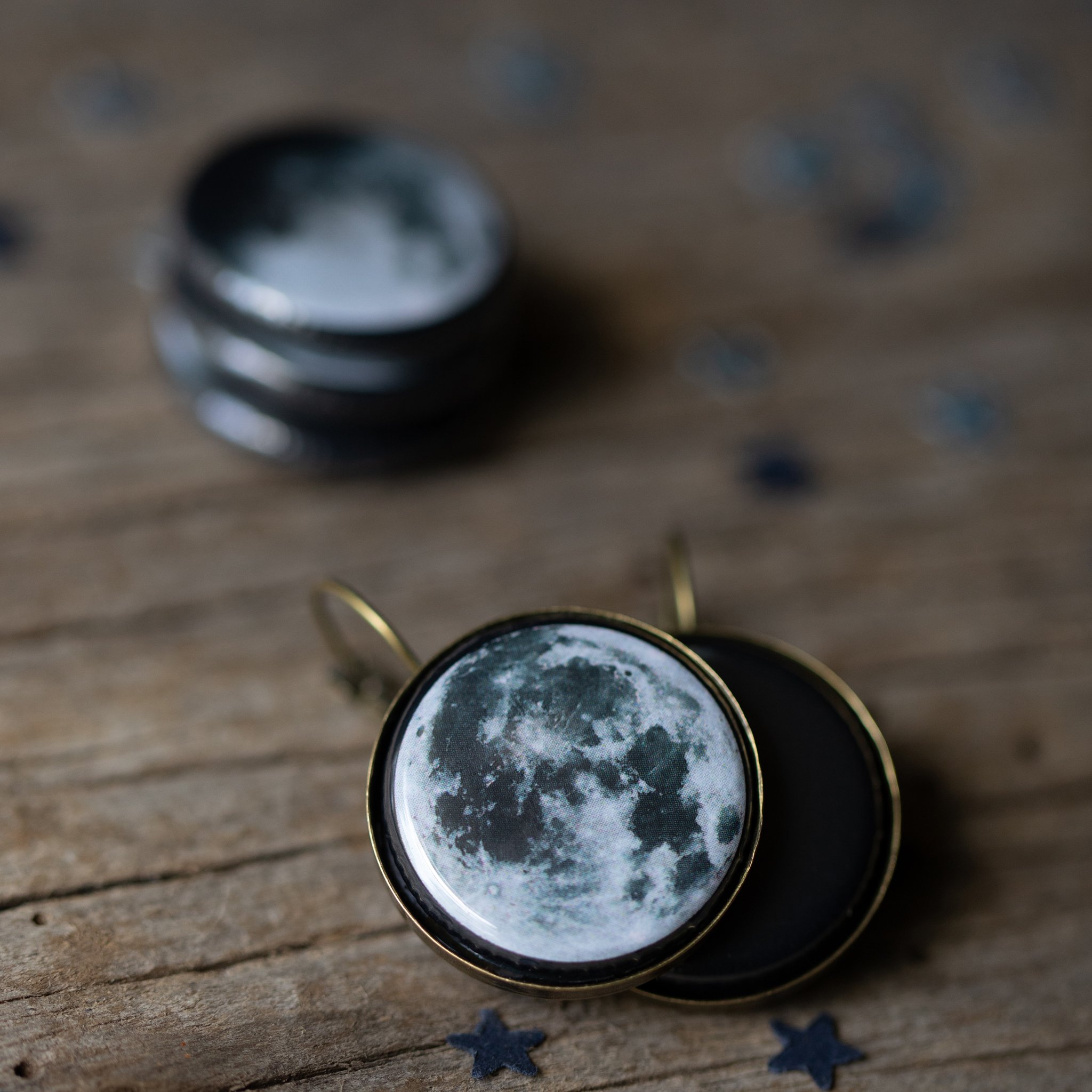 A pair of interchangeable earrings featuring five moon phases, available in silver and bronze tones, showcasing their unique magnetic design.