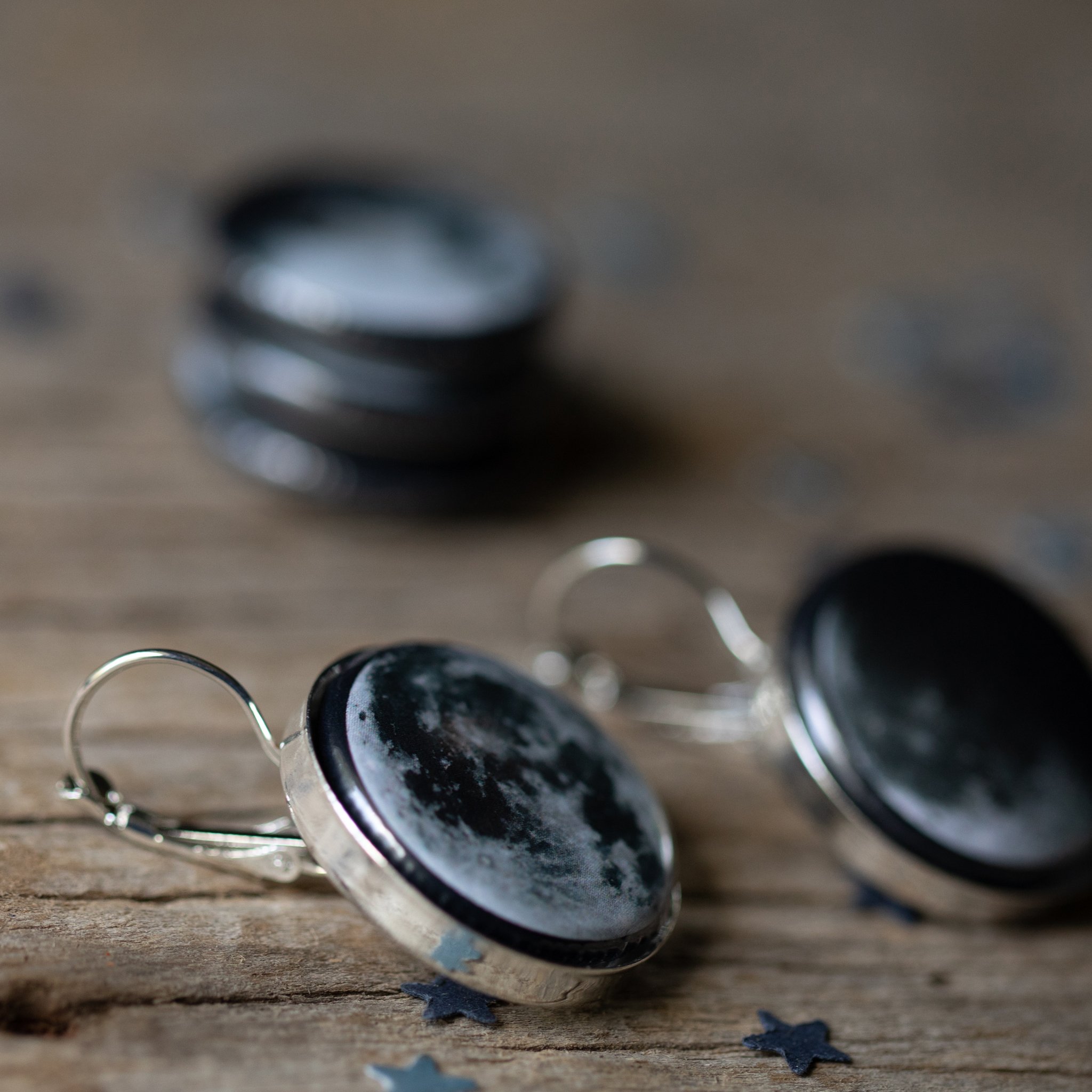 A pair of interchangeable earrings featuring five moon phases, available in silver and bronze tones, showcasing their unique magnetic design.