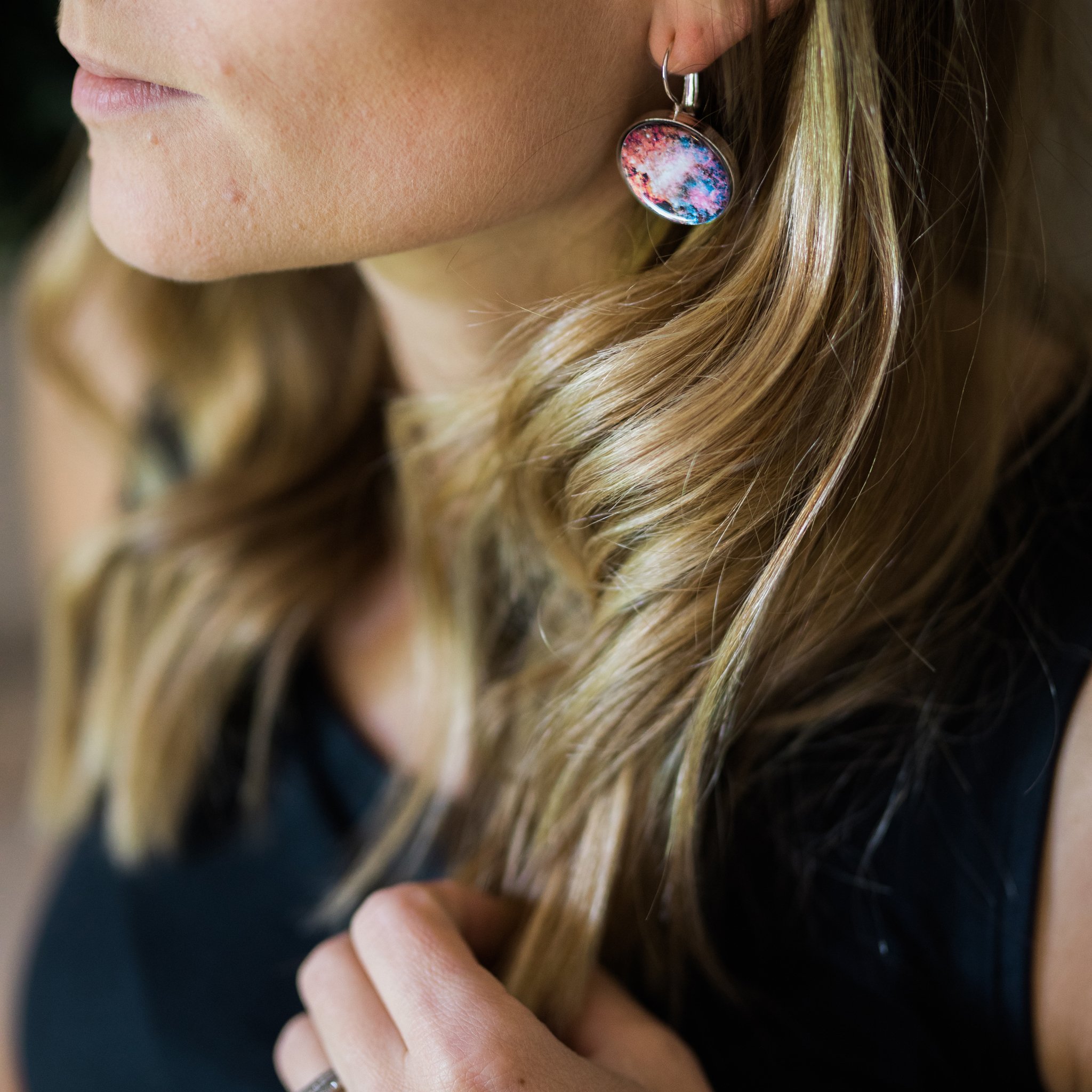 A pair of Interchangeable Nebula Earrings showcasing vibrant cosmic designs, available in silver and bronze tones, with a strong magnetic hold.