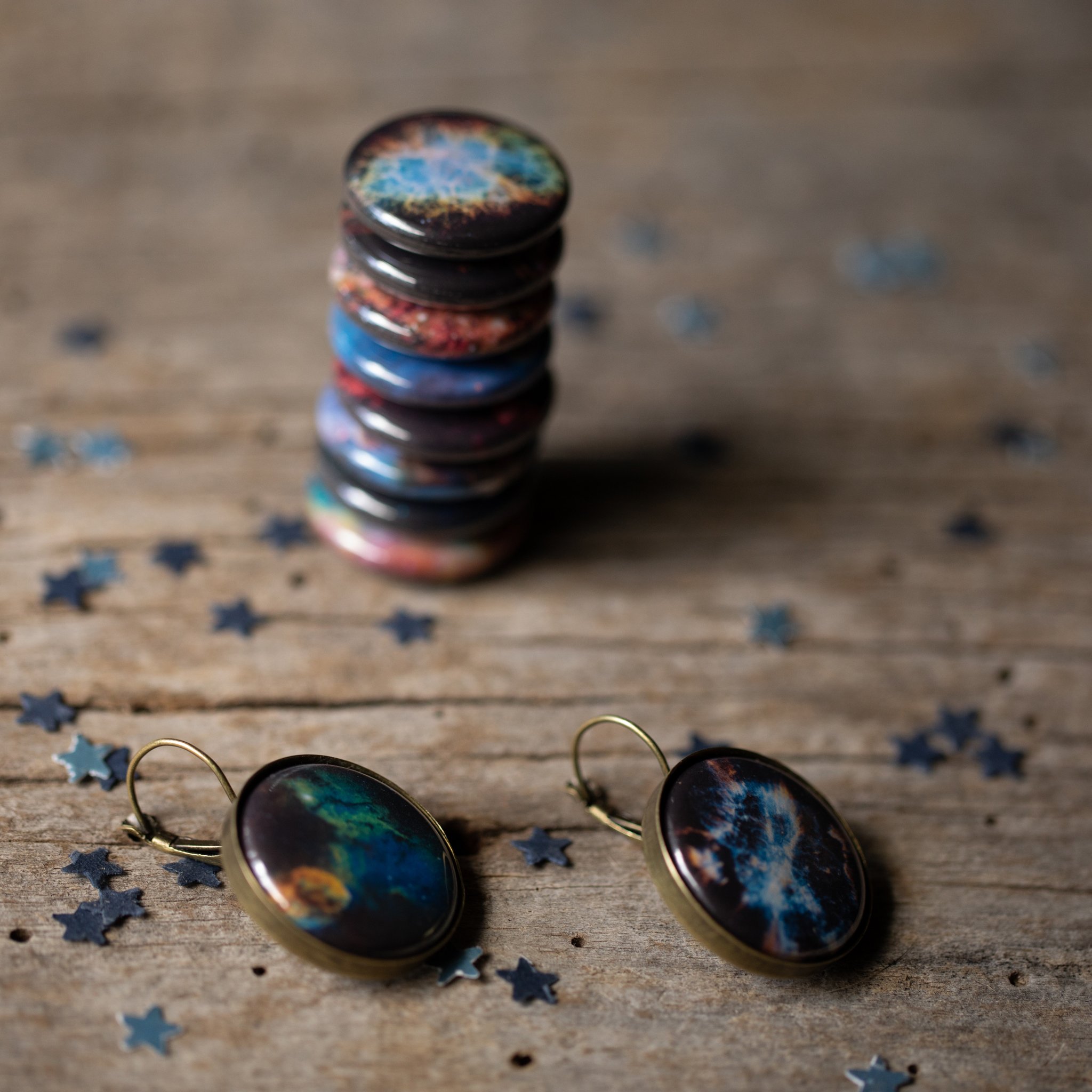 A pair of Interchangeable Nebula Earrings showcasing vibrant cosmic designs, available in silver and bronze tones, with a strong magnetic hold.