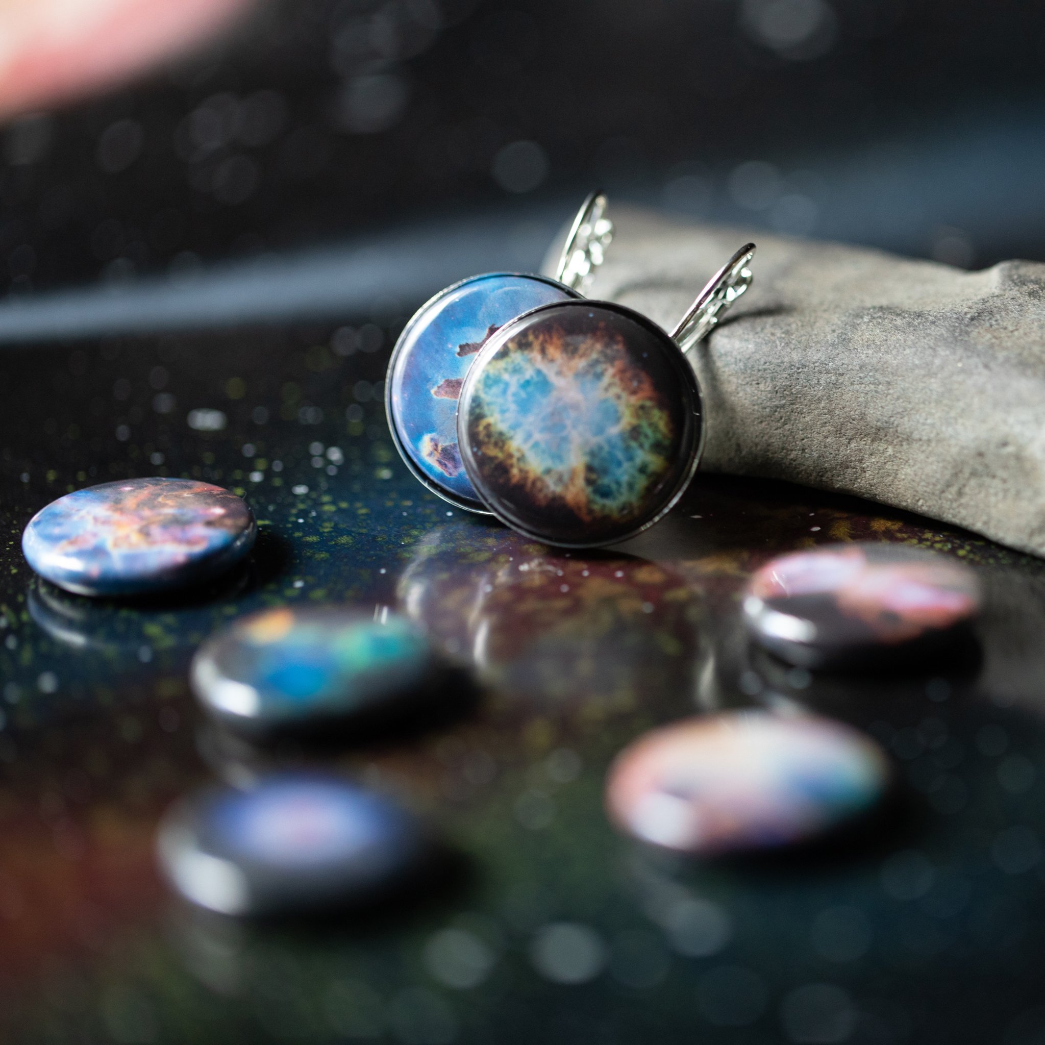 A pair of Interchangeable Nebula Earrings showcasing vibrant cosmic designs, available in silver and bronze tones, with a strong magnetic hold.