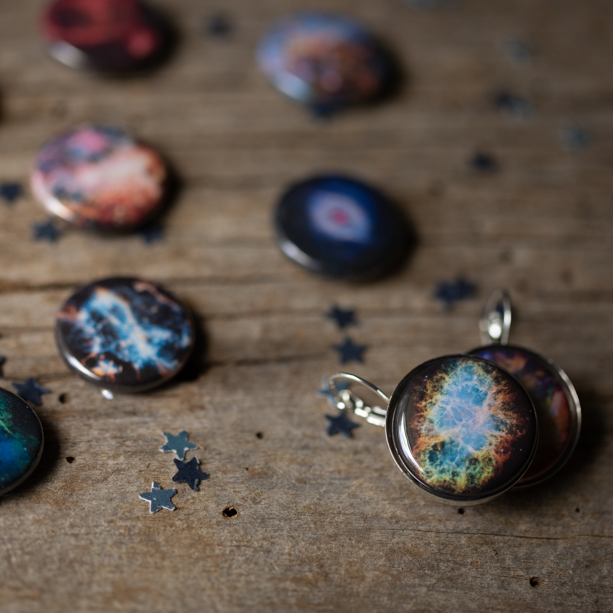 A pair of Interchangeable Nebula Earrings showcasing vibrant cosmic designs, available in silver and bronze tones, with a strong magnetic hold.