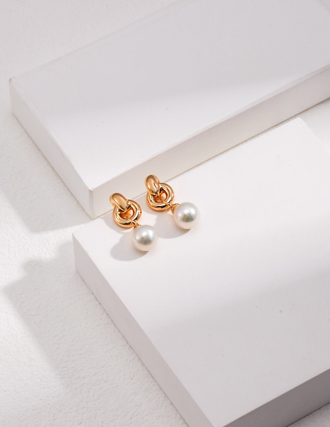 A pair of elegant interlocking natural pearl earrings featuring freshwater pearls and gold vermeil, showcasing their unique design and craftsmanship.