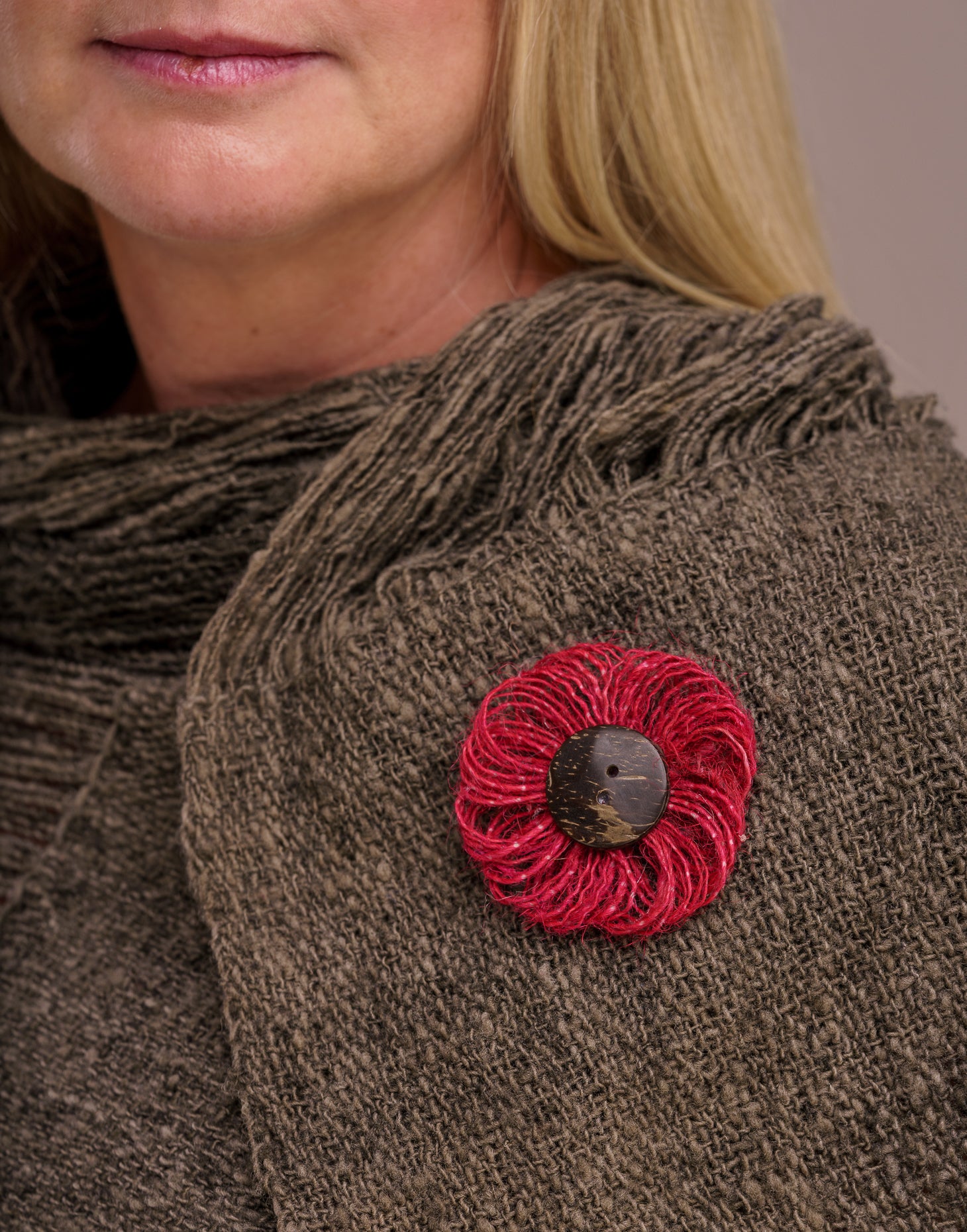 A delicate jute flower brooch featuring a coconut button at the center, showcasing natural fibers and a charming design.