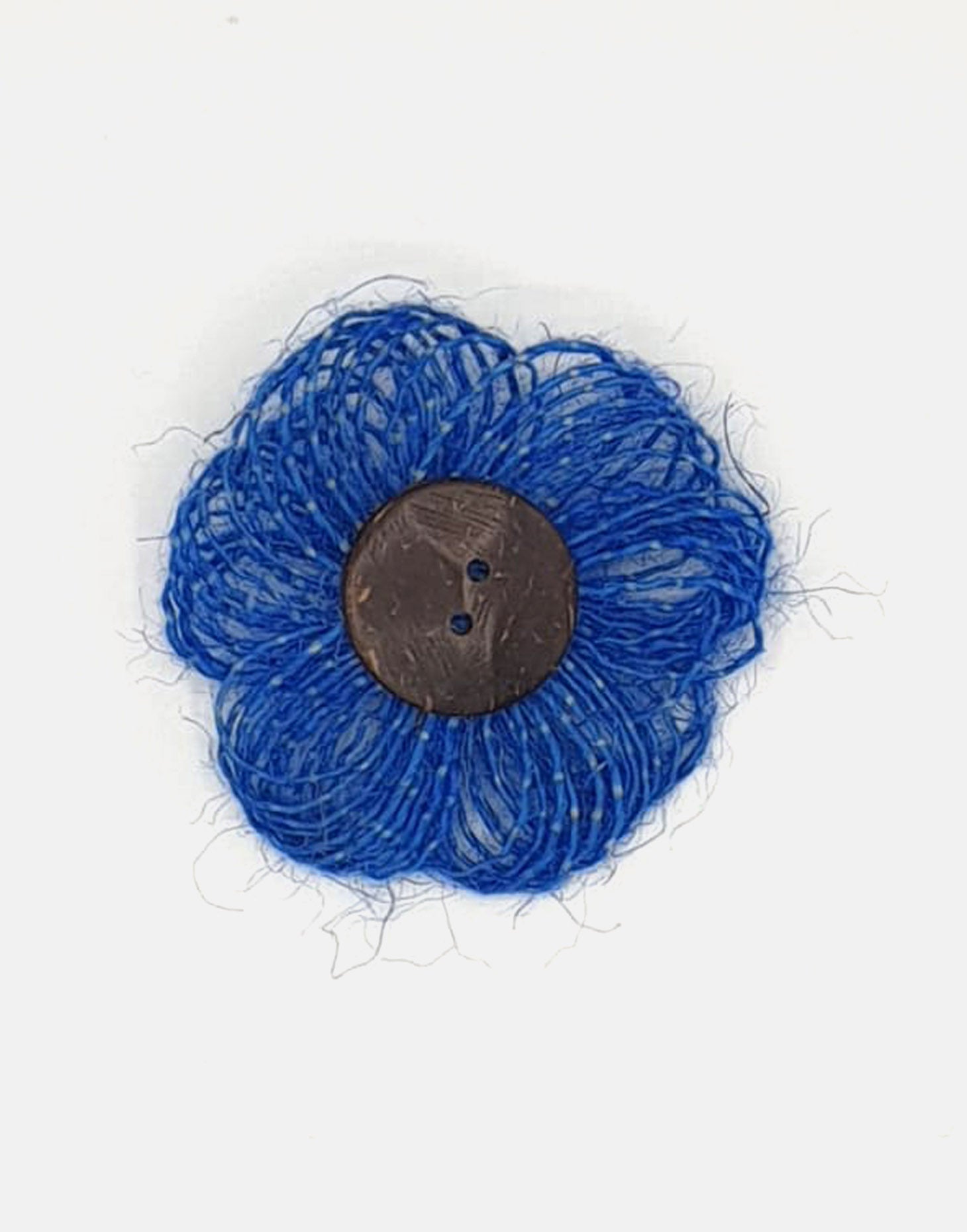 A delicate jute flower brooch featuring a coconut button at the center, showcasing natural fibers and a charming design.