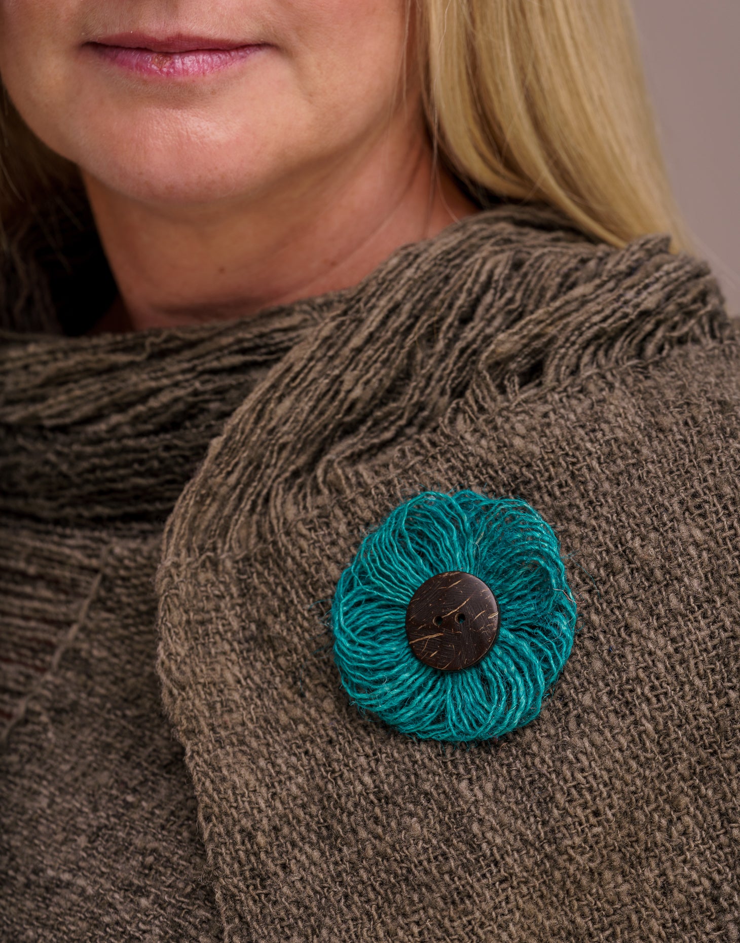 A delicate jute flower brooch featuring a coconut button at the center, showcasing natural fibers and a charming design.