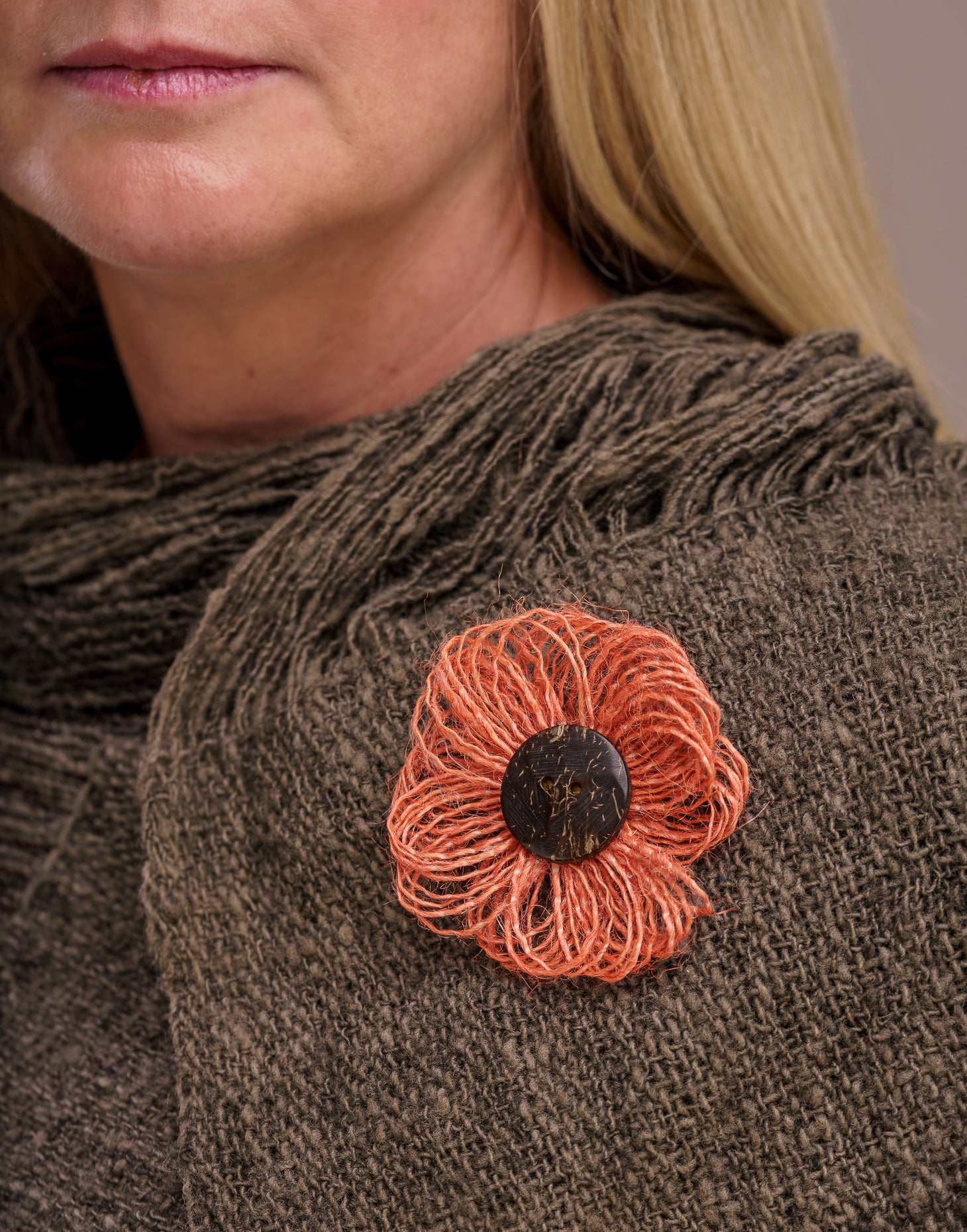 A delicate jute flower brooch featuring a coconut button at the center, showcasing natural fibers and a charming design.