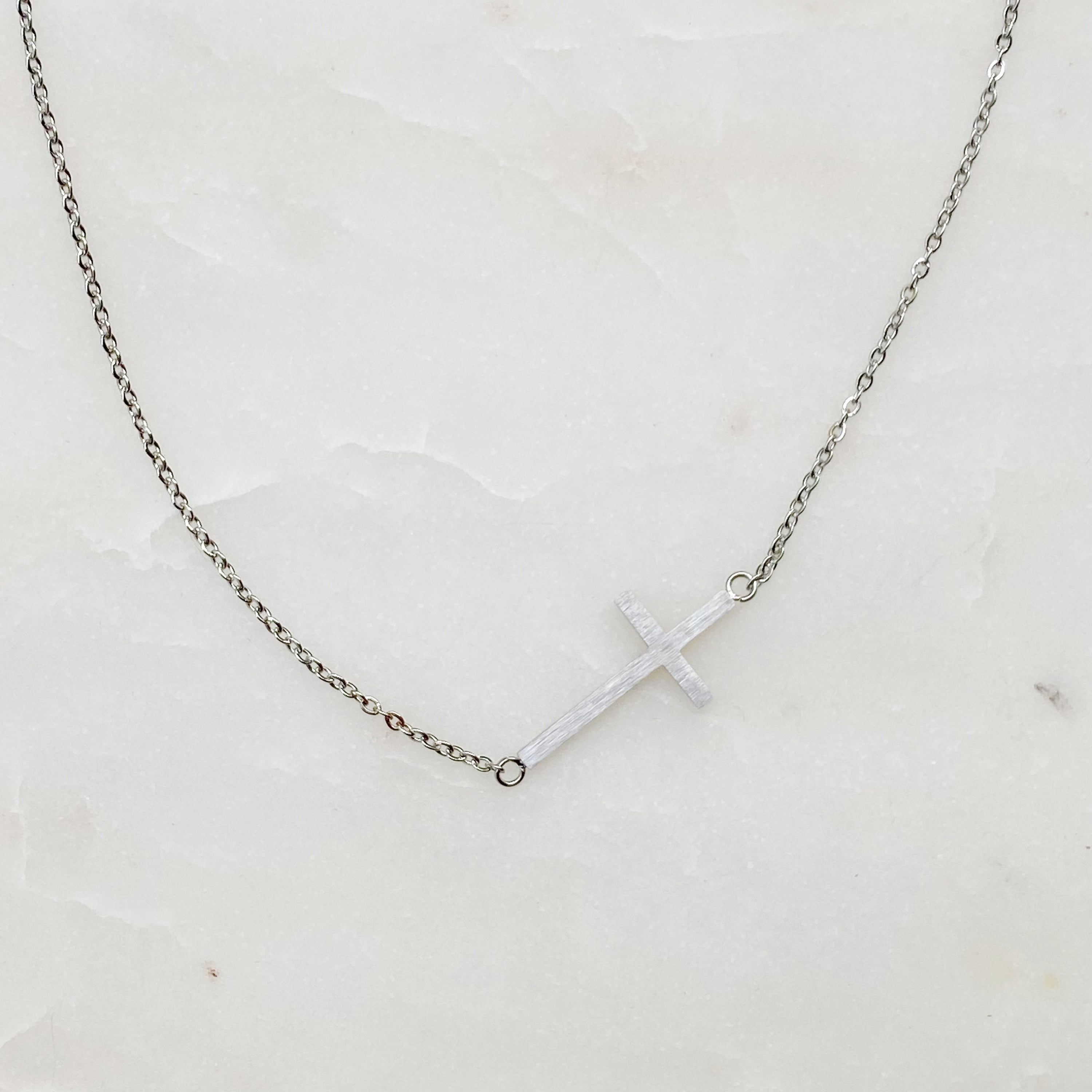 Kayla Cross Necklace featuring a side hanging cross design on a 16-inch chain, elegantly plated in 18K gold.