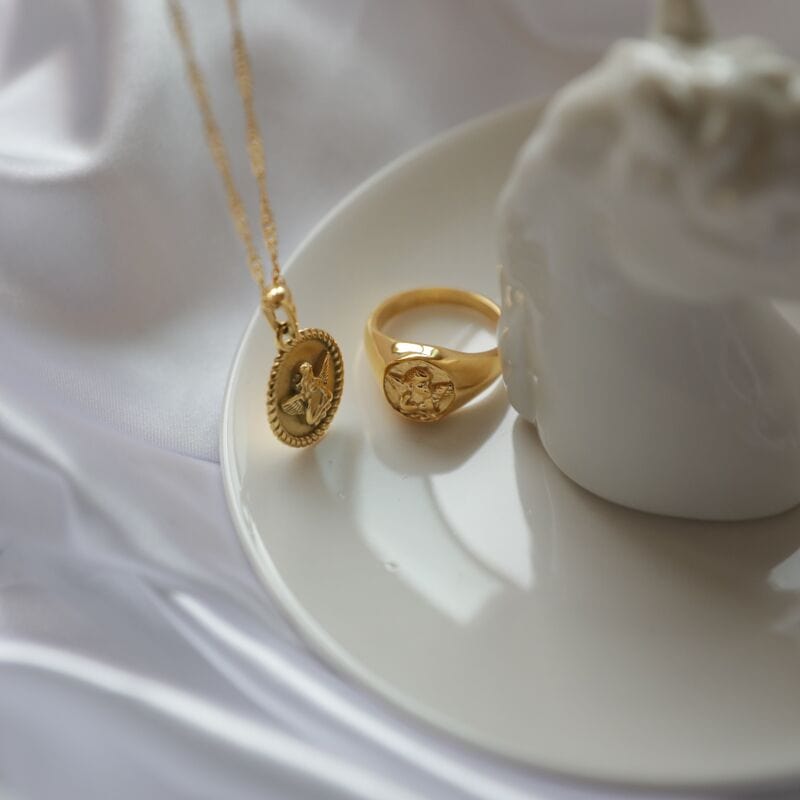 Kiki Carved Angel Baby Signet Ring showcasing a chunky gold and silver design with a carved angel motif.