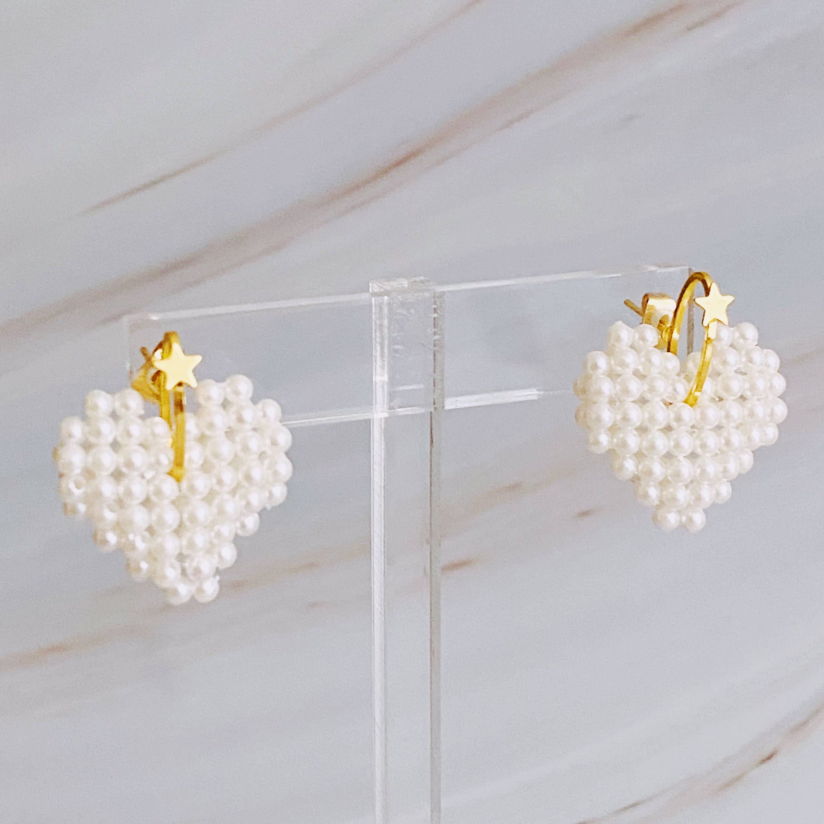 A pair of stylish Knitted Pearl Heart Earrings featuring a knitted pearl heart design with a golden star accent, perfect for any occasion.