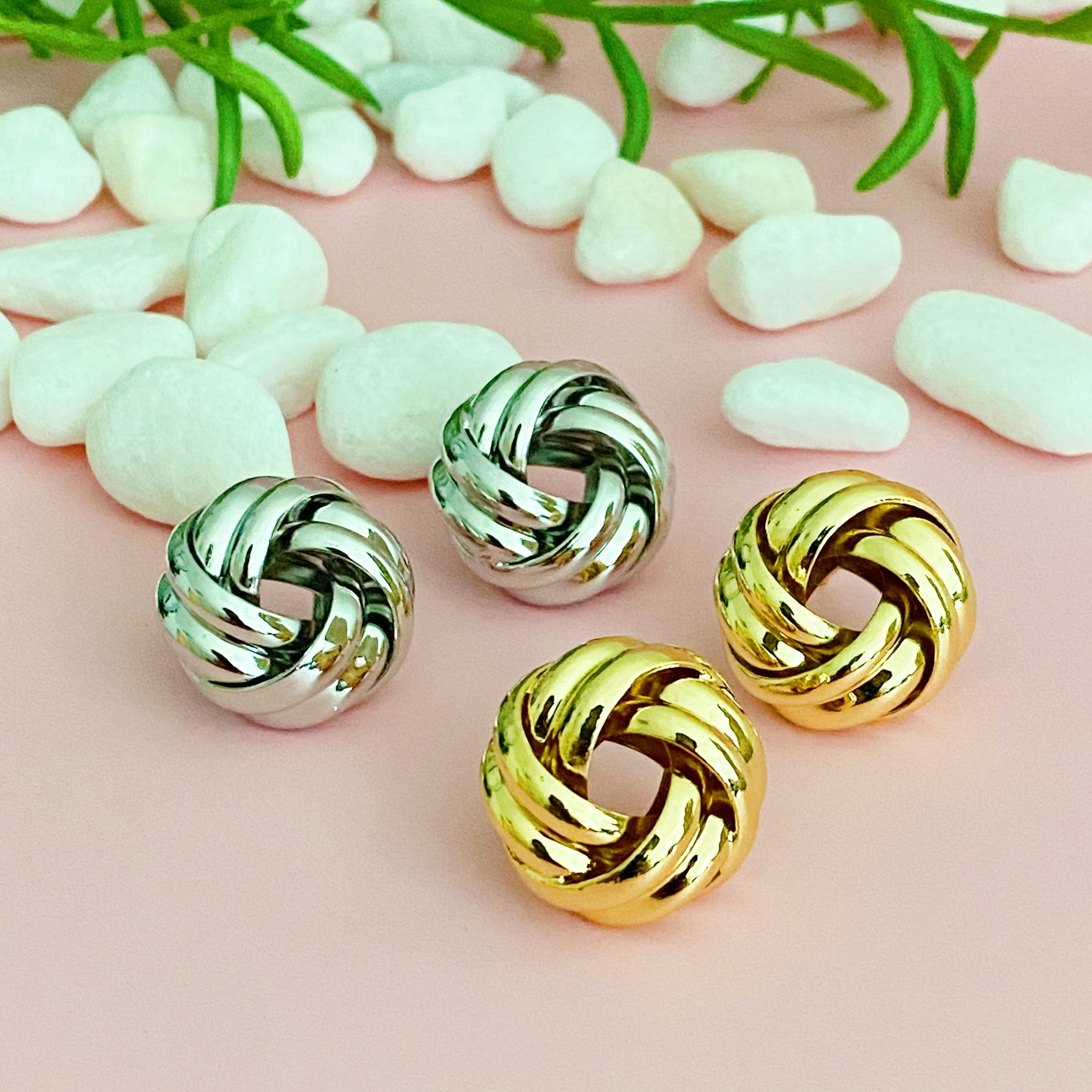 A pair of elegant knotted design stud earrings in polished gold and silver finishes, showcasing their sophisticated craftsmanship.