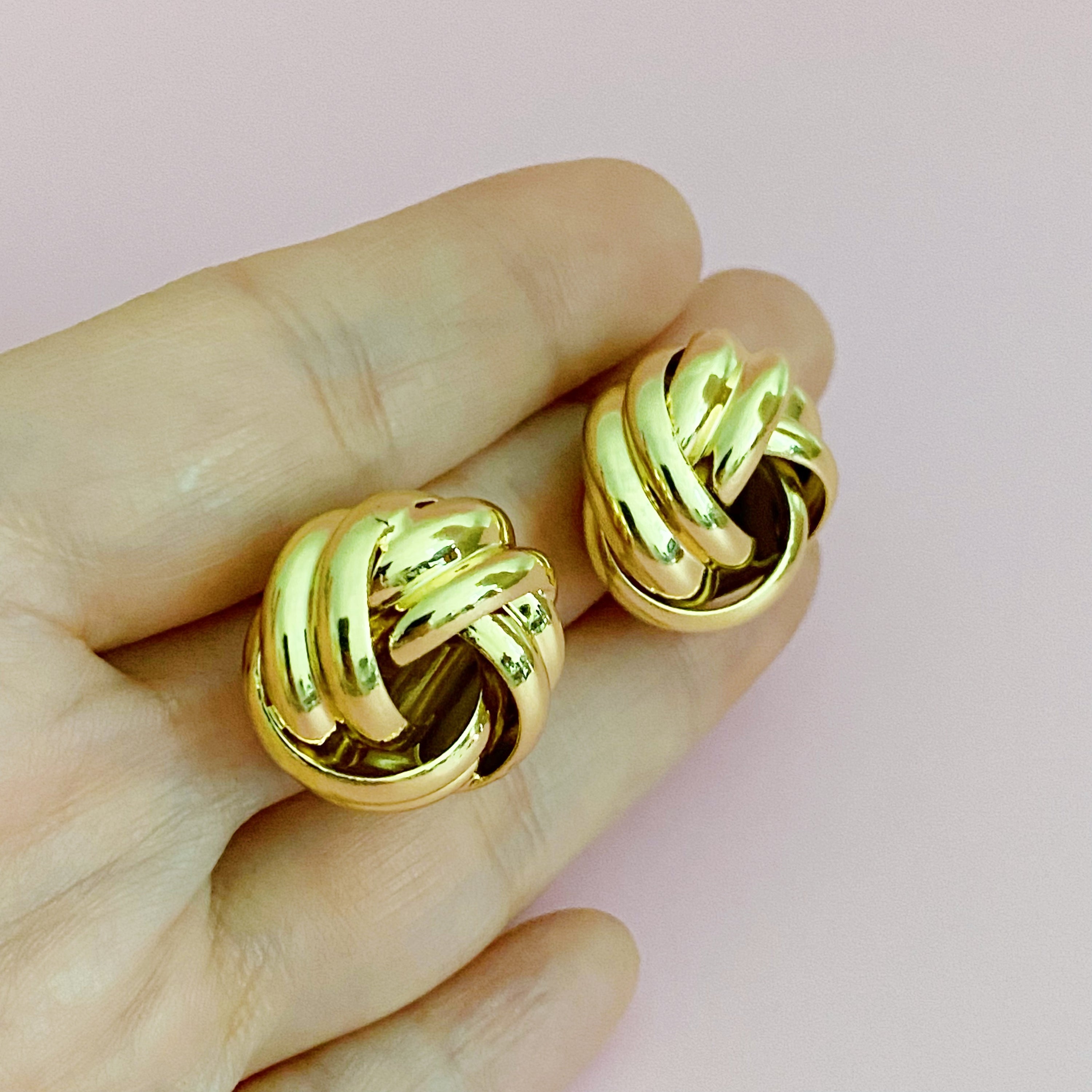 A pair of elegant knotted design stud earrings in polished gold and silver finishes, showcasing their sophisticated craftsmanship.