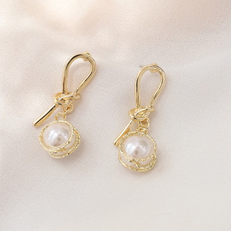 Elegant knotted gold wired earrings featuring a single artificial pearl, perfect for stylish occasions.