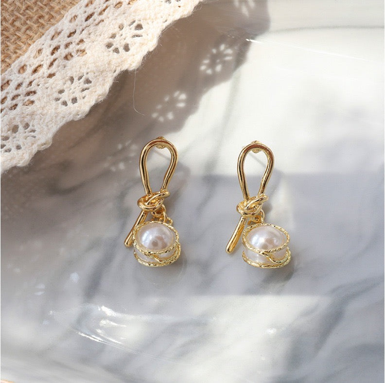 Elegant knotted gold wired earrings featuring a single artificial pearl, perfect for stylish occasions.