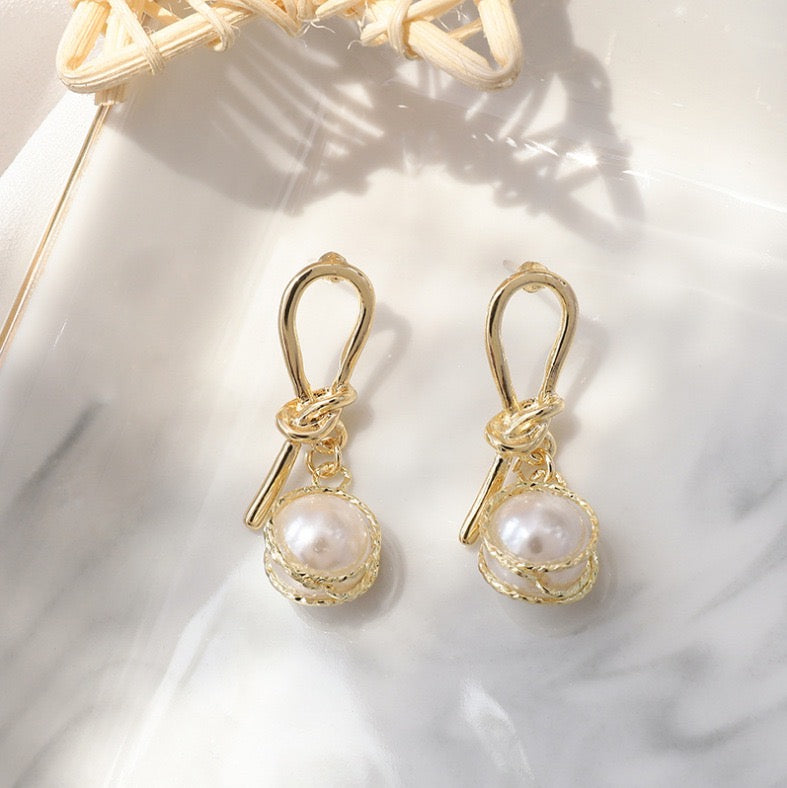 Elegant knotted gold wired earrings featuring a single artificial pearl, perfect for stylish occasions.