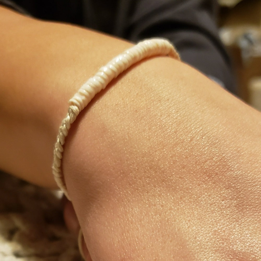 Lakey Braided Puka Bracelet featuring cotton cords, coconut shell clasps, and puka shell beads in natural neutral tones.