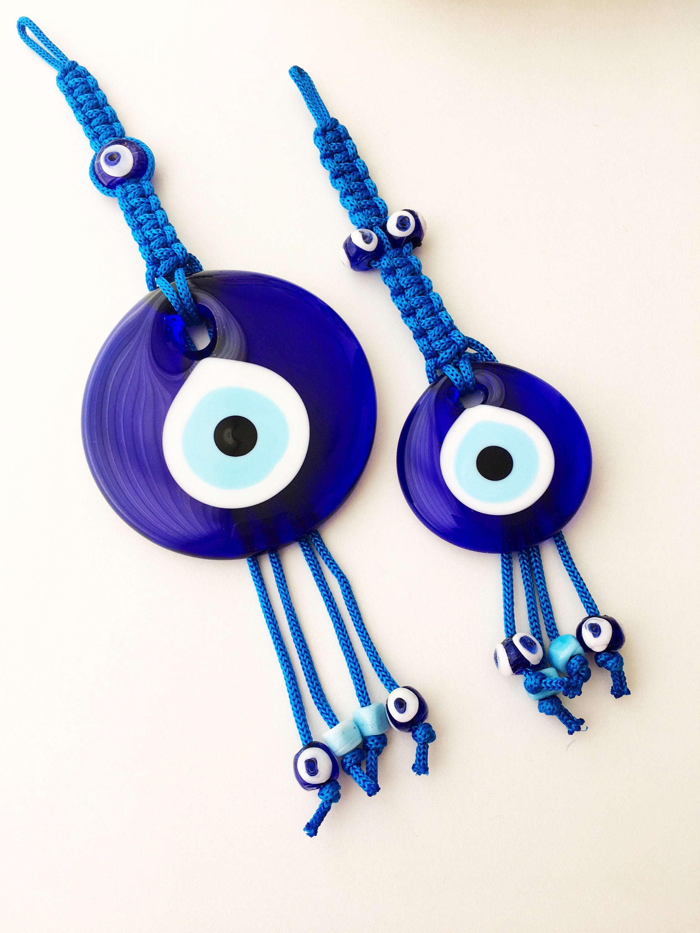 A large blue evil eye wall hanging featuring a central big evil eye bead surrounded by smaller evil eye beads, showcasing intricate macrame design.