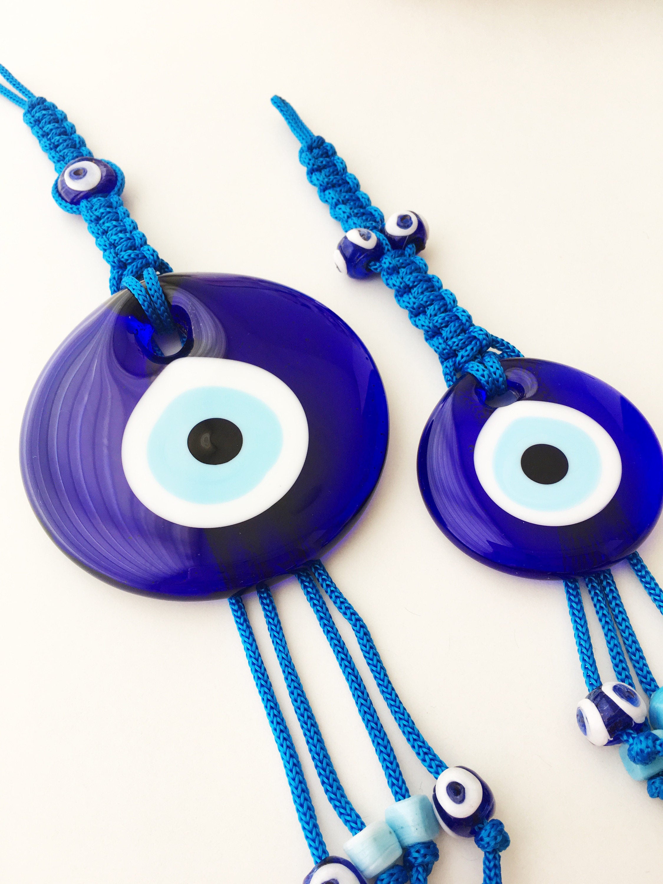 A large blue evil eye wall hanging featuring a central big evil eye bead surrounded by smaller evil eye beads, showcasing intricate macrame design.