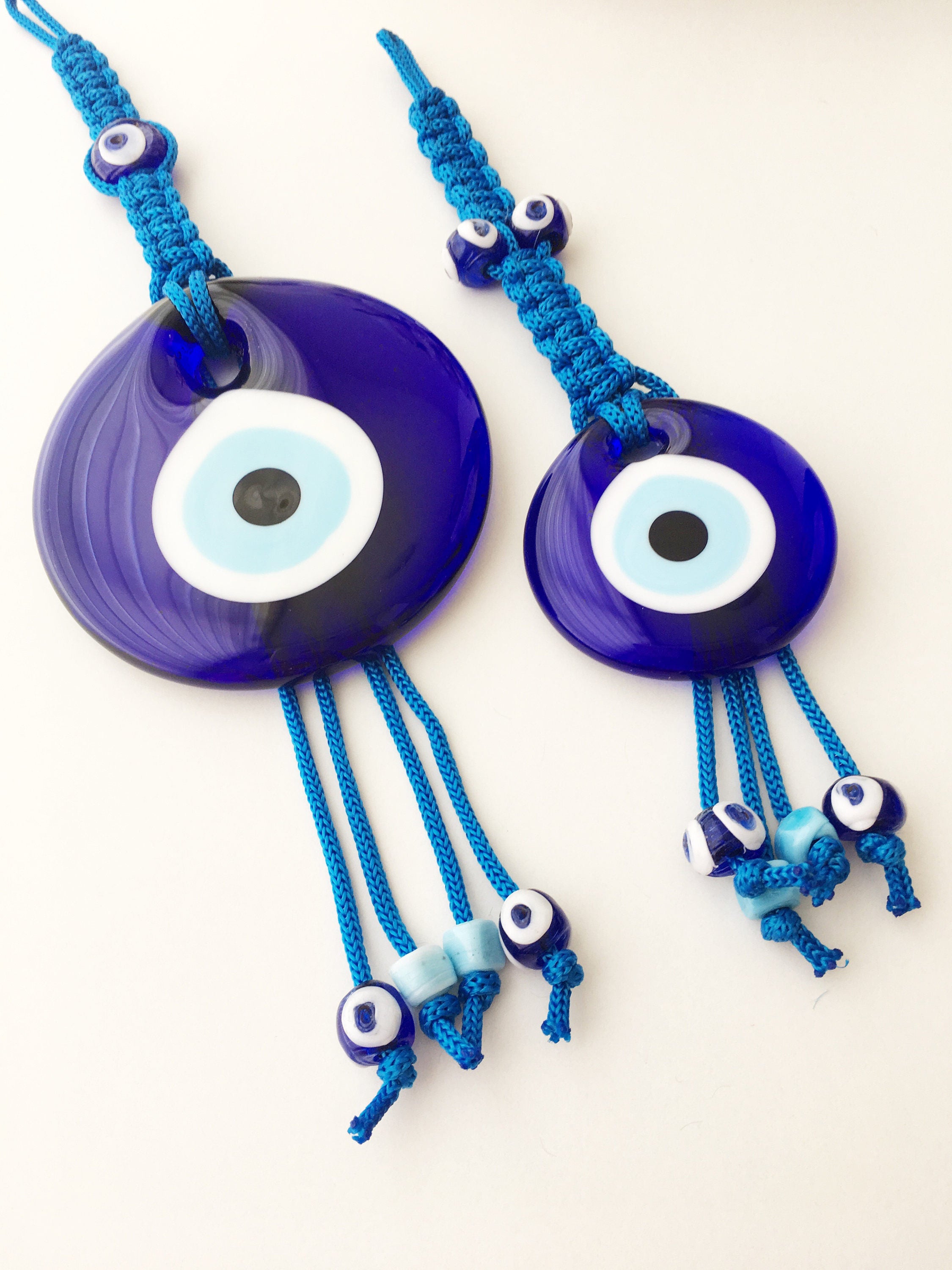 A large blue evil eye wall hanging featuring a central big evil eye bead surrounded by smaller evil eye beads, showcasing intricate macrame design.