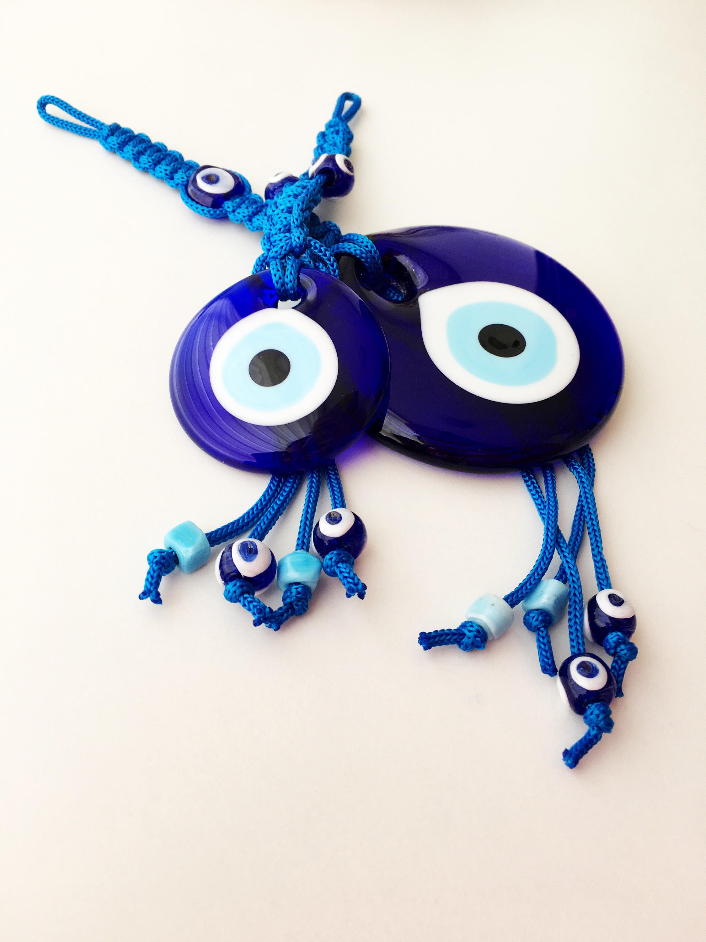 A large blue evil eye wall hanging featuring a central big evil eye bead surrounded by smaller evil eye beads, showcasing intricate macrame design.