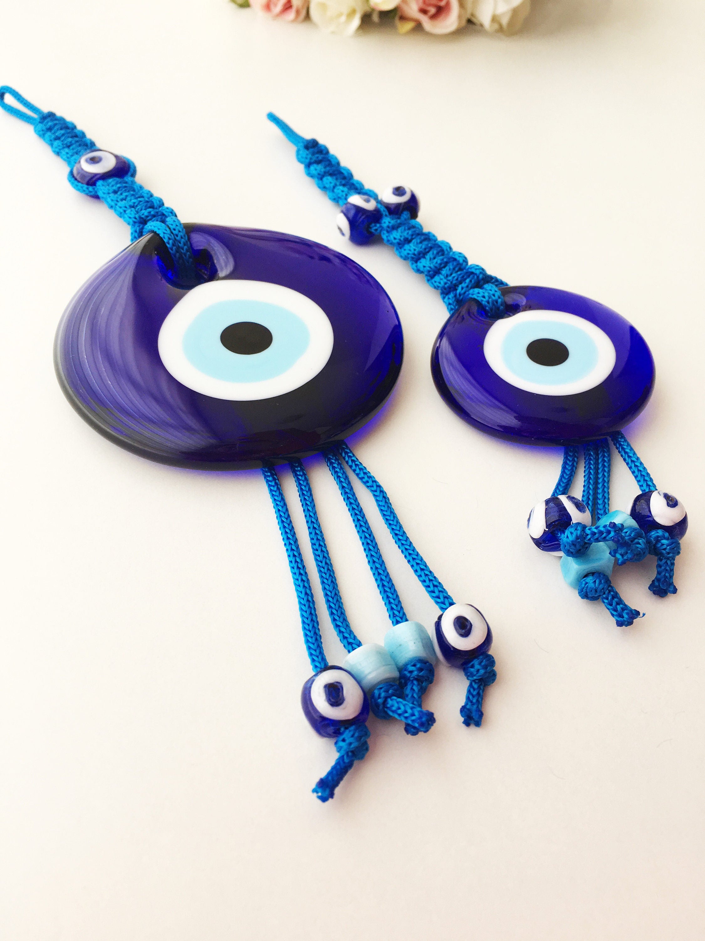 A large blue evil eye wall hanging featuring a central big evil eye bead surrounded by smaller evil eye beads, showcasing intricate macrame design.