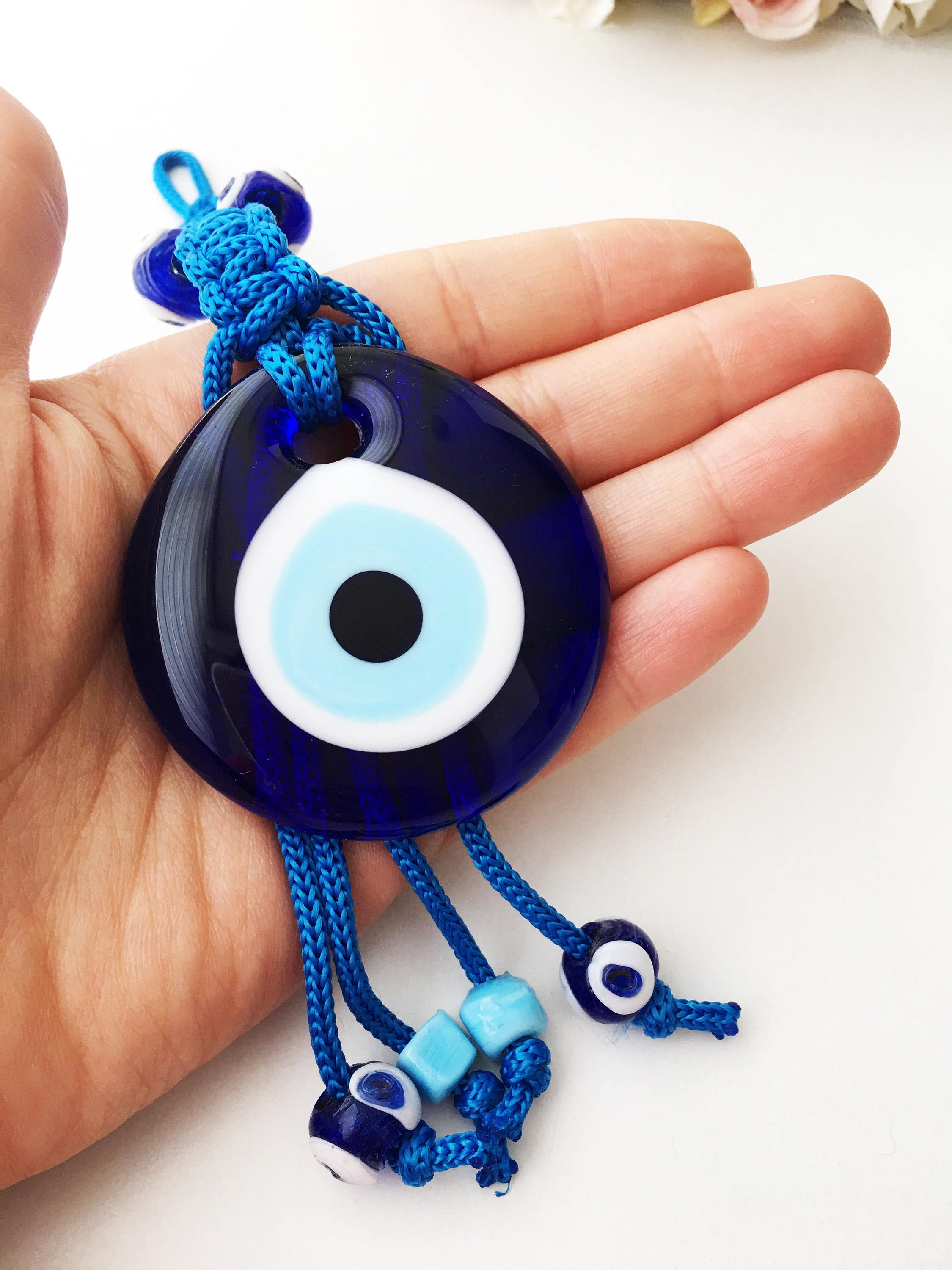 A large blue evil eye wall hanging featuring a central big evil eye bead surrounded by smaller evil eye beads, showcasing intricate macrame design.