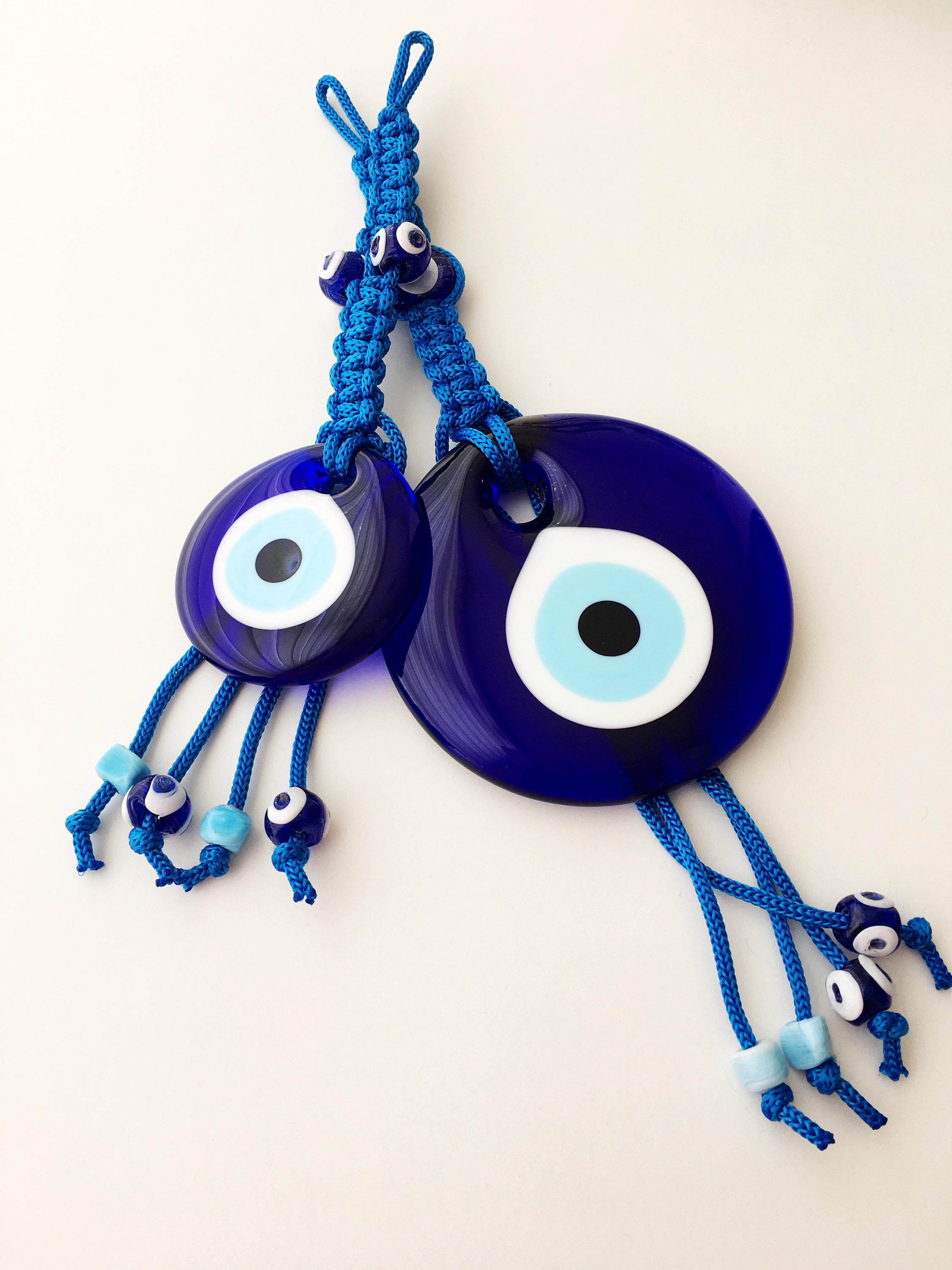 A large blue evil eye wall hanging featuring a central big evil eye bead surrounded by smaller evil eye beads, showcasing intricate macrame design.