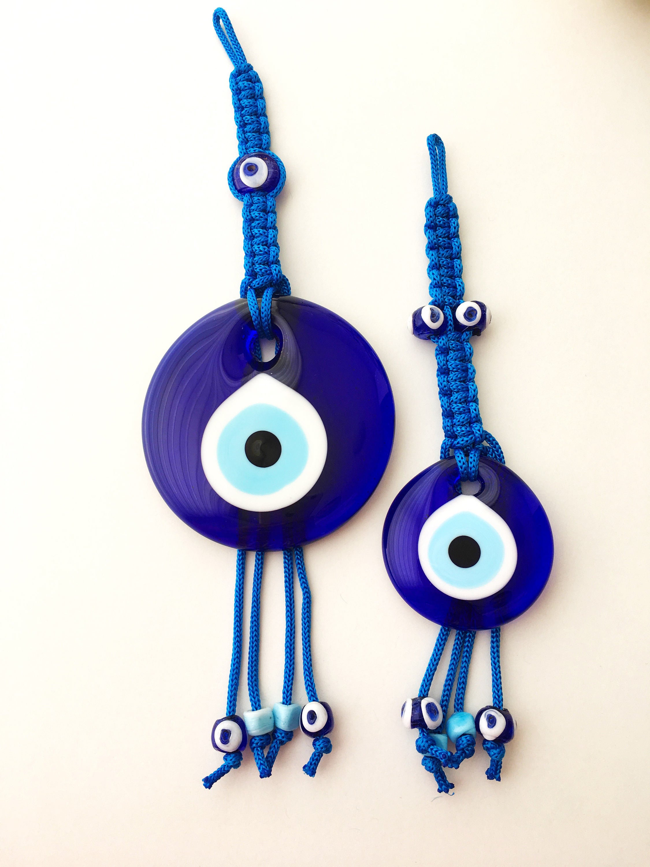 A large blue evil eye wall hanging featuring a central big evil eye bead surrounded by smaller evil eye beads, showcasing intricate macrame design.