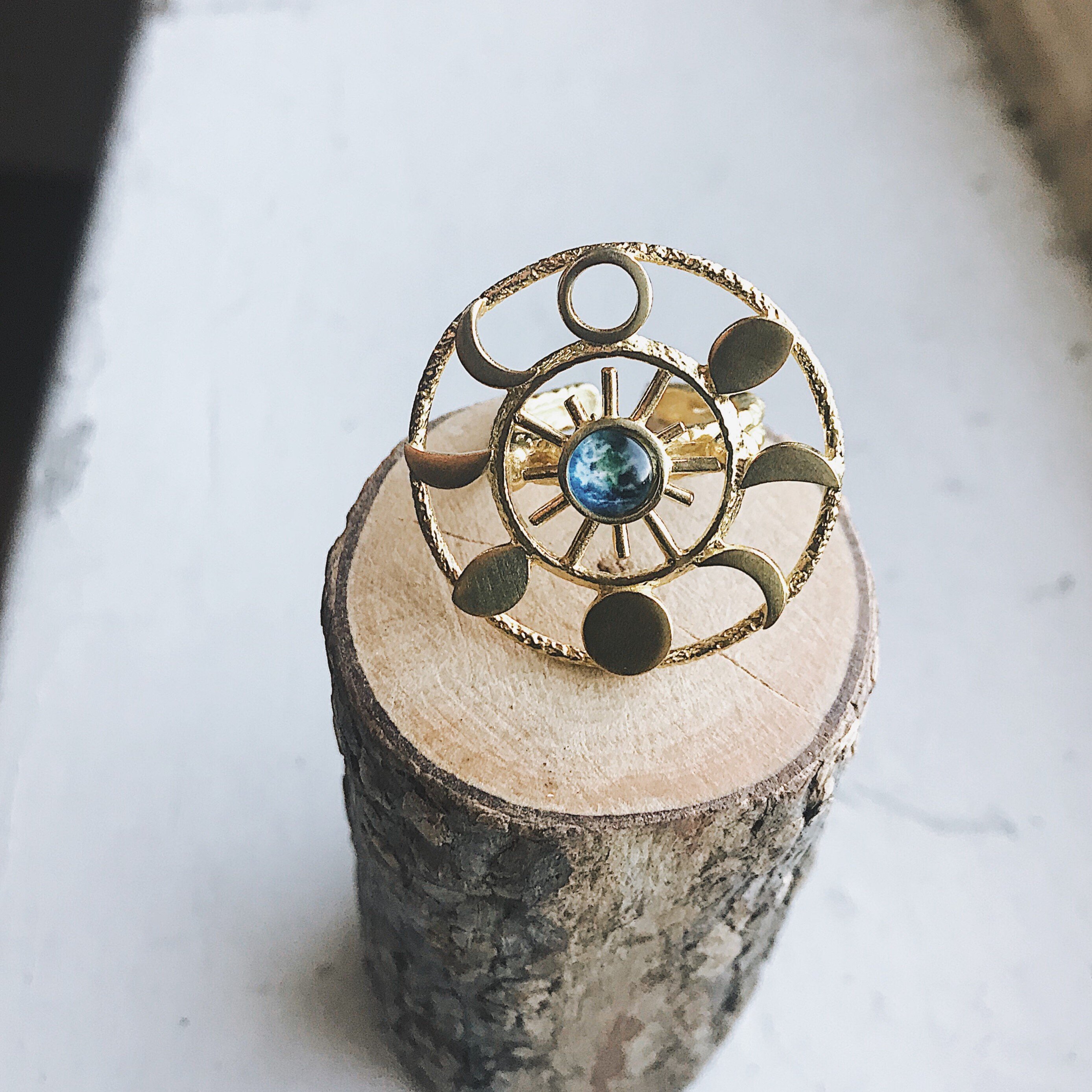 Large Moon Phase Statement Cocktail Ring featuring Earth in glass surrounded by eight moon phases in a textured raw brass gold tone.