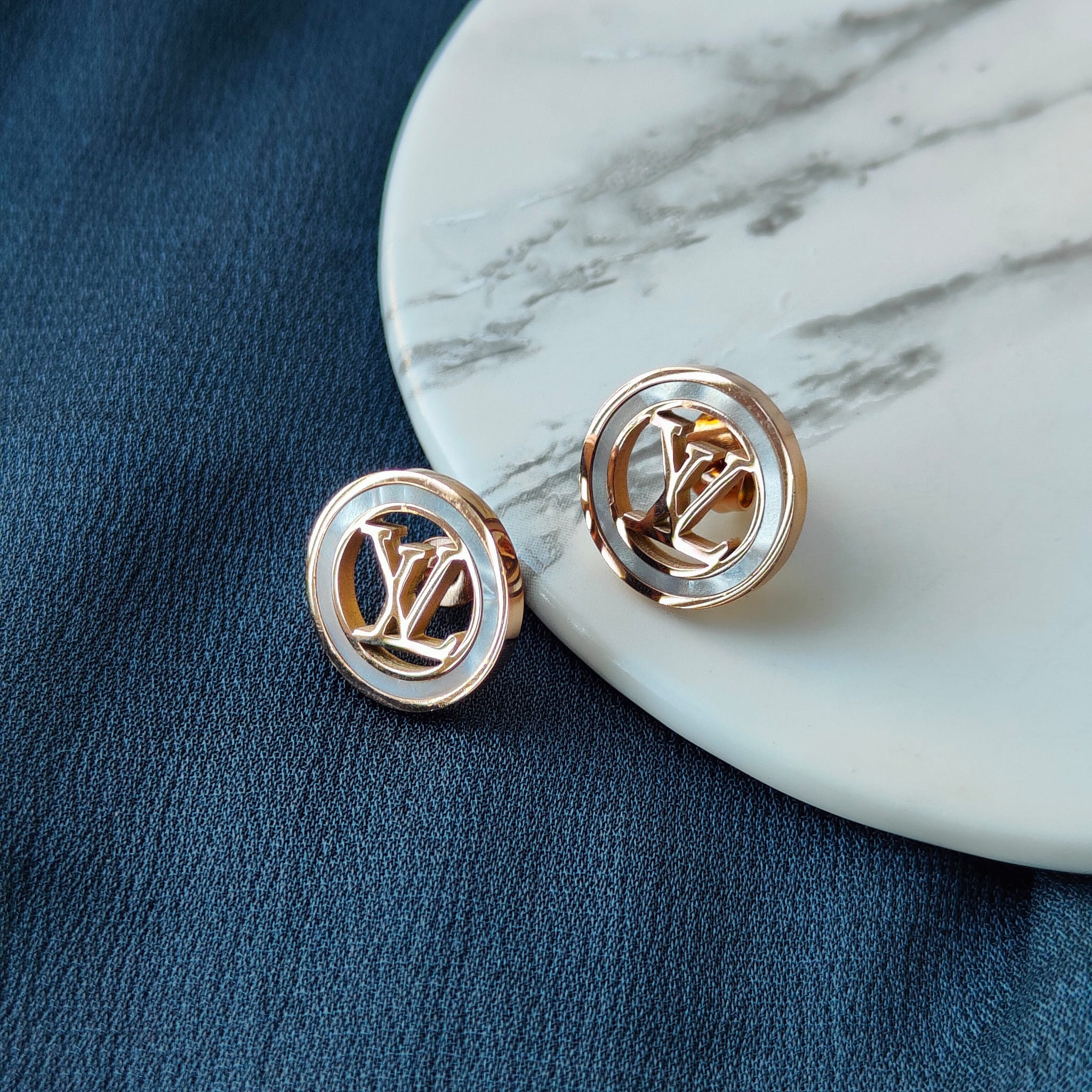 Large round elegant rose gold plated stud earrings with white enamel accents, showcasing a contemporary design.