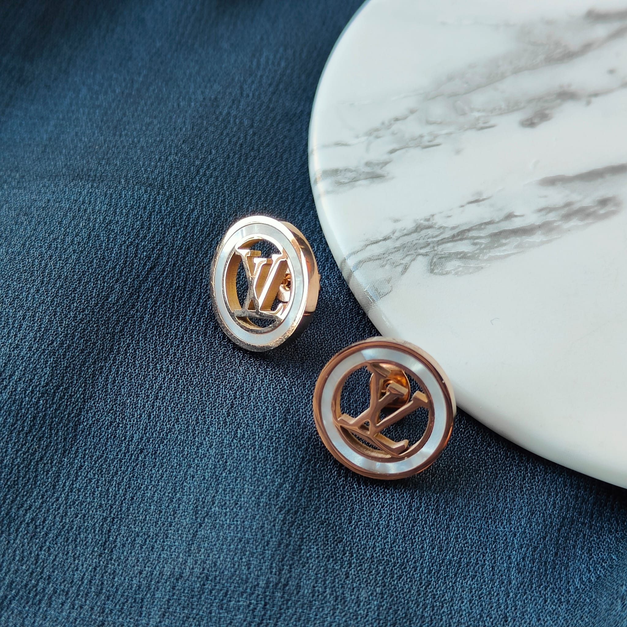 Large round elegant rose gold plated stud earrings with white enamel accents, showcasing a contemporary design.