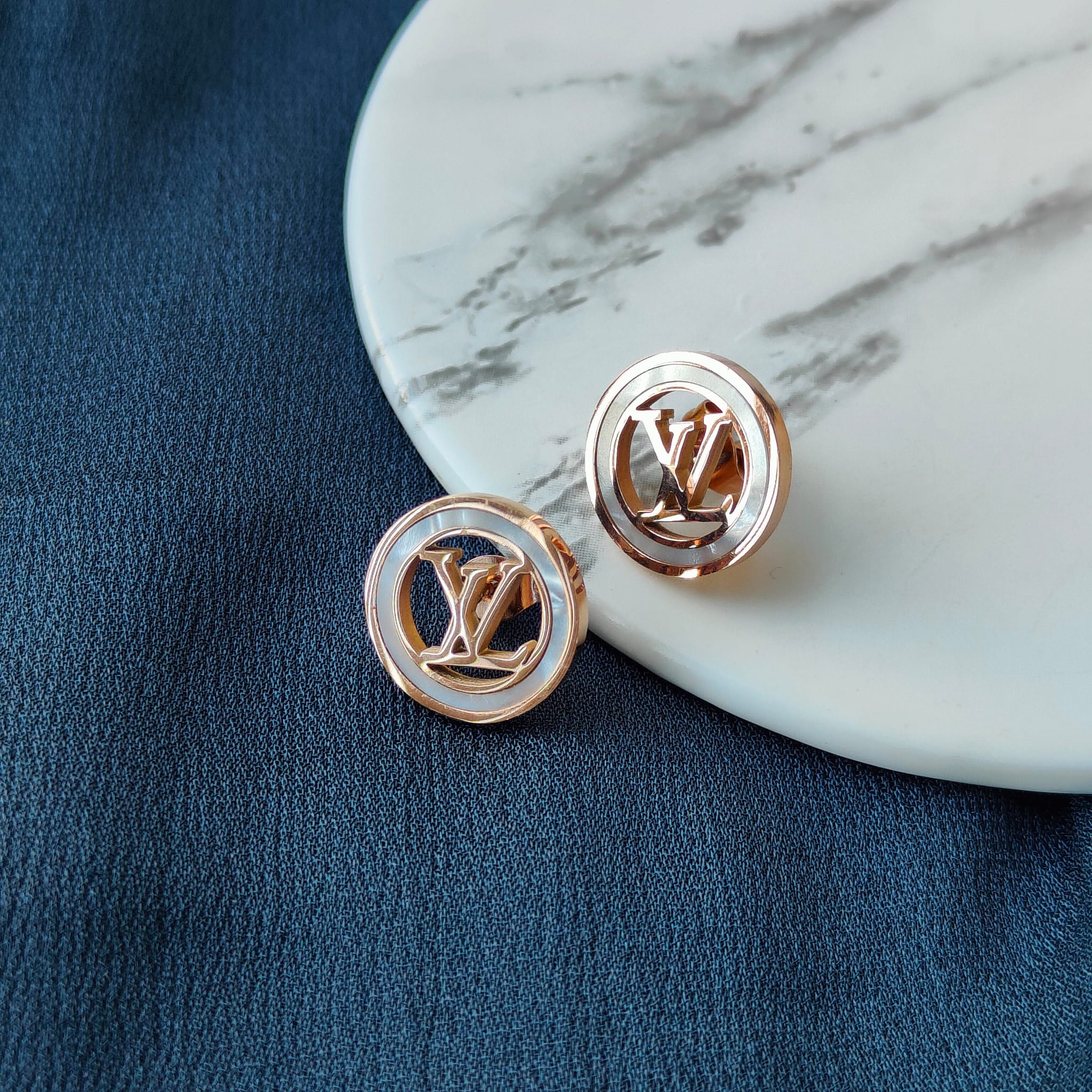 Large round elegant rose gold plated stud earrings with white enamel accents, showcasing a contemporary design.