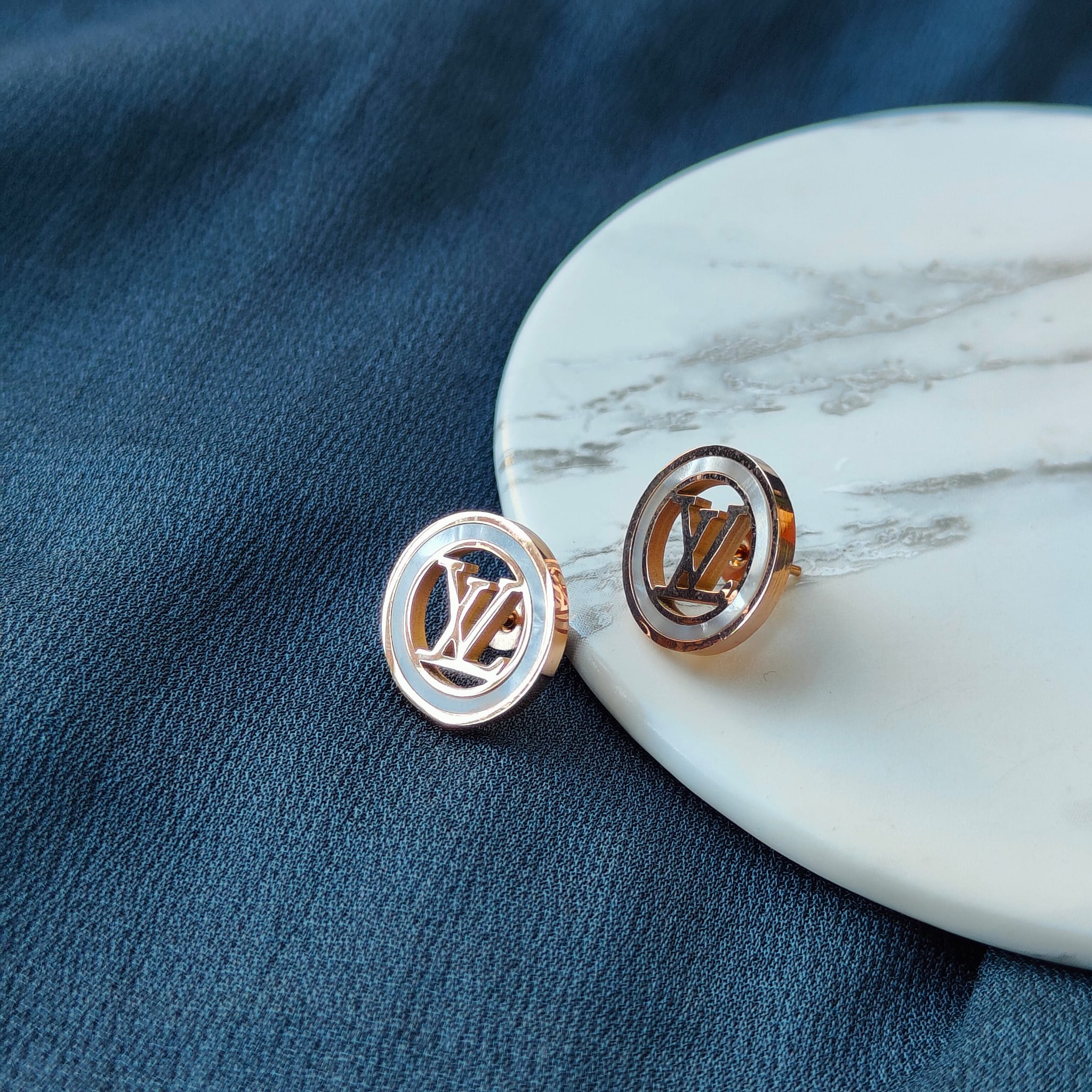 Large round elegant rose gold plated stud earrings with white enamel accents, showcasing a contemporary design.