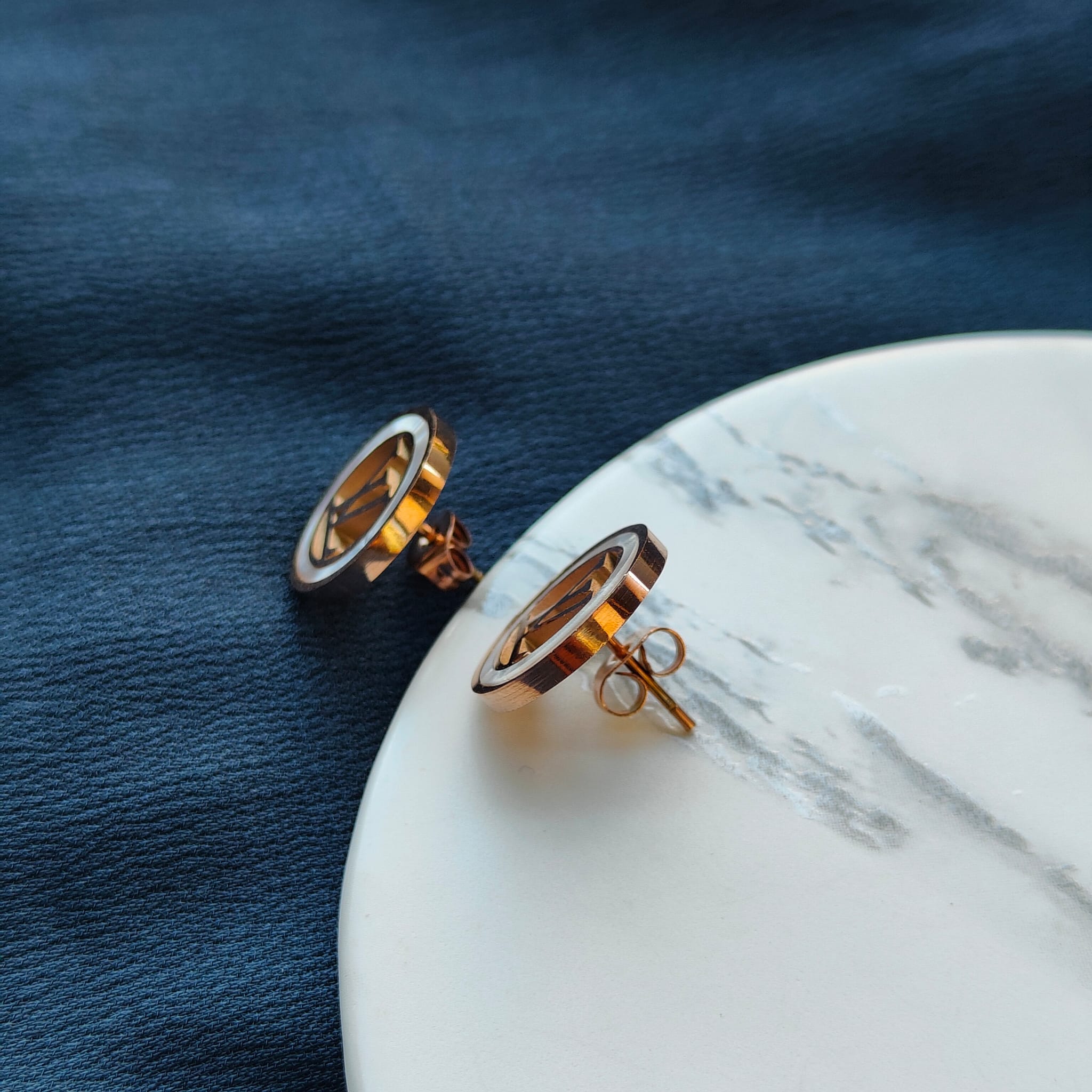 Large round elegant rose gold plated stud earrings with white enamel accents, showcasing a contemporary design.