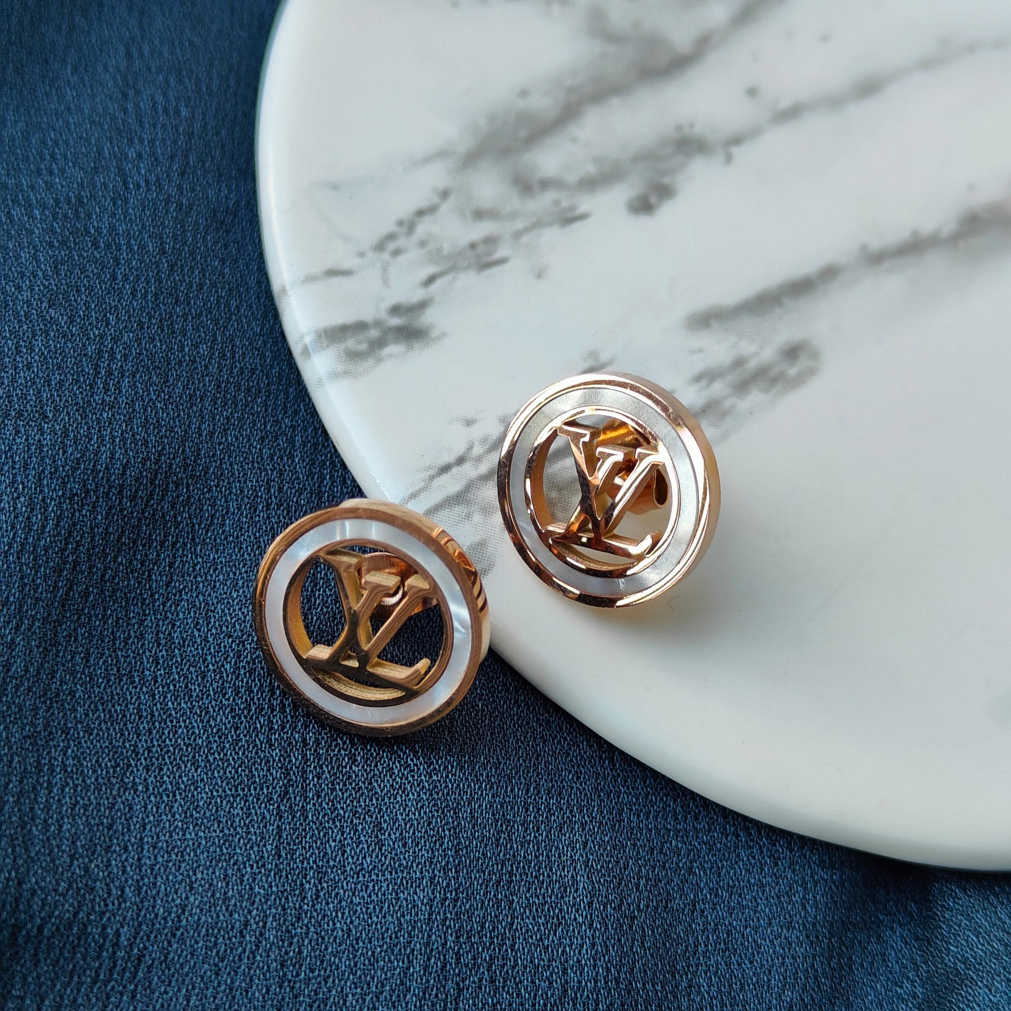 Large round elegant rose gold plated stud earrings with white enamel accents, showcasing a contemporary design.