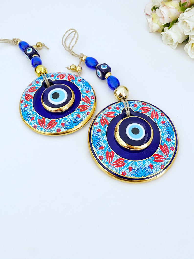 A beautifully handpainted Larger Evil Eye Wall Hanging featuring a large glass round evil eye and smaller evil eyes, perfect for home decor.