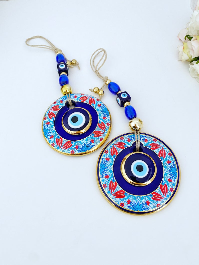 A beautifully handpainted Larger Evil Eye Wall Hanging featuring a large glass round evil eye and smaller evil eyes, perfect for home decor.