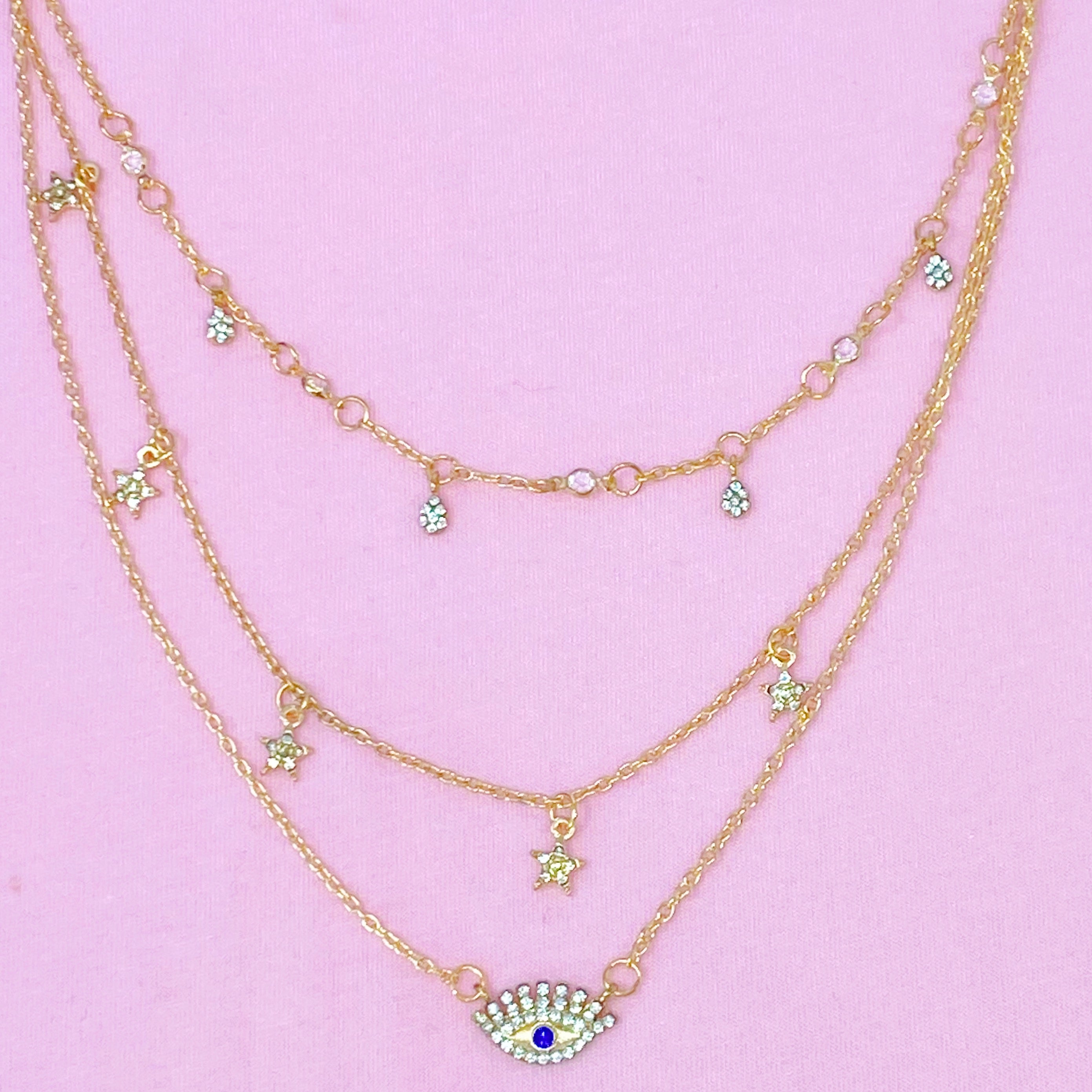 Layered Admiration Necklace featuring triple layers with stars and eye elements in gold-tone plated alloy.