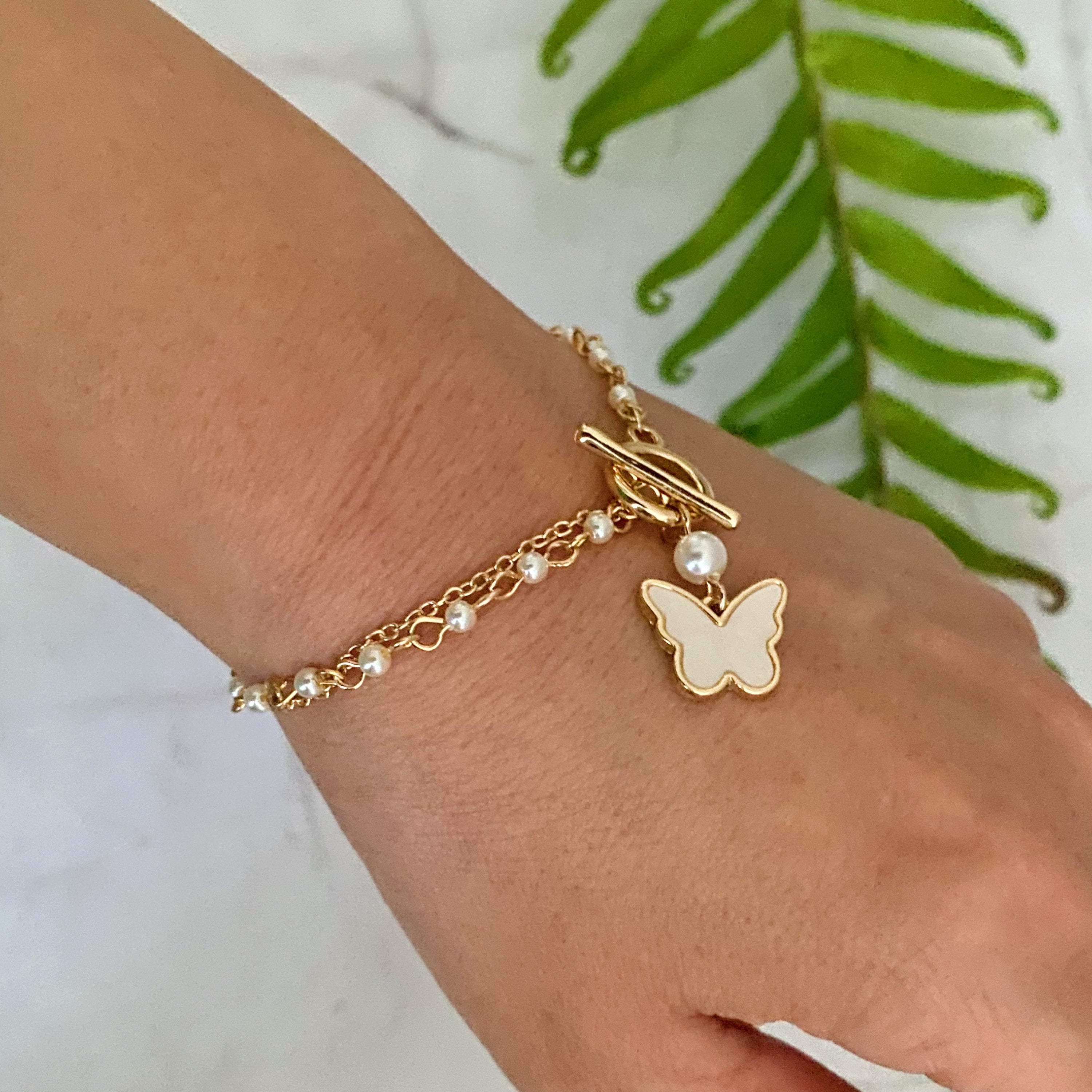 Layered Pearl Chain Butterfly Bracelet featuring pearl mix chains and a butterfly charm, elegantly designed for versatile wear.