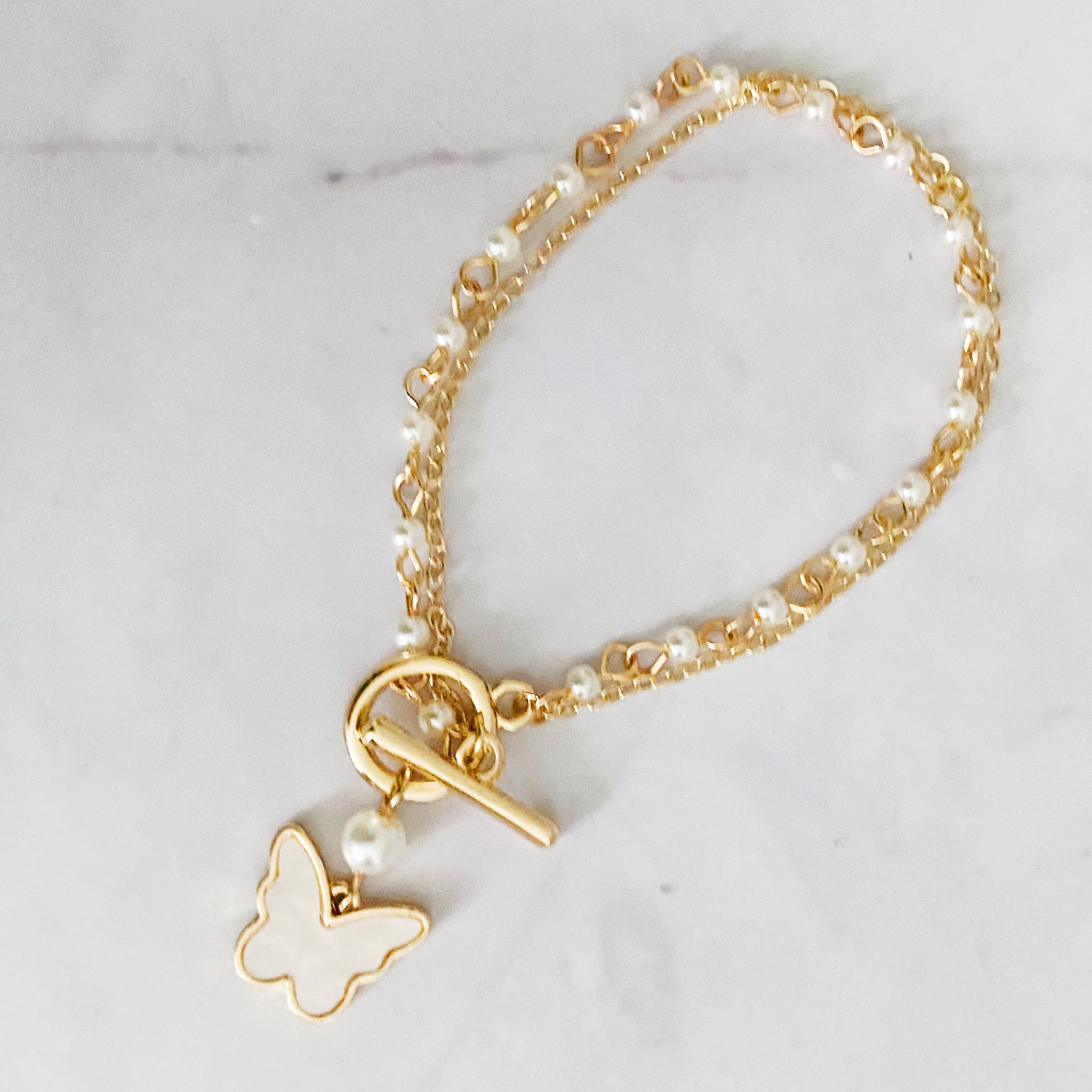 Layered Pearl Chain Butterfly Bracelet featuring pearl mix chains and a butterfly charm, elegantly designed for versatile wear.