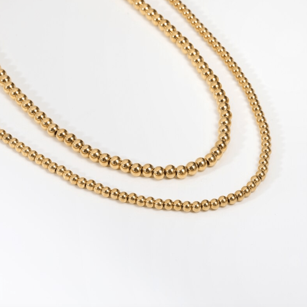 Leonidas Ball Beaded Necklace featuring gold beaded design and stainless steel material, showcasing elegance and durability.