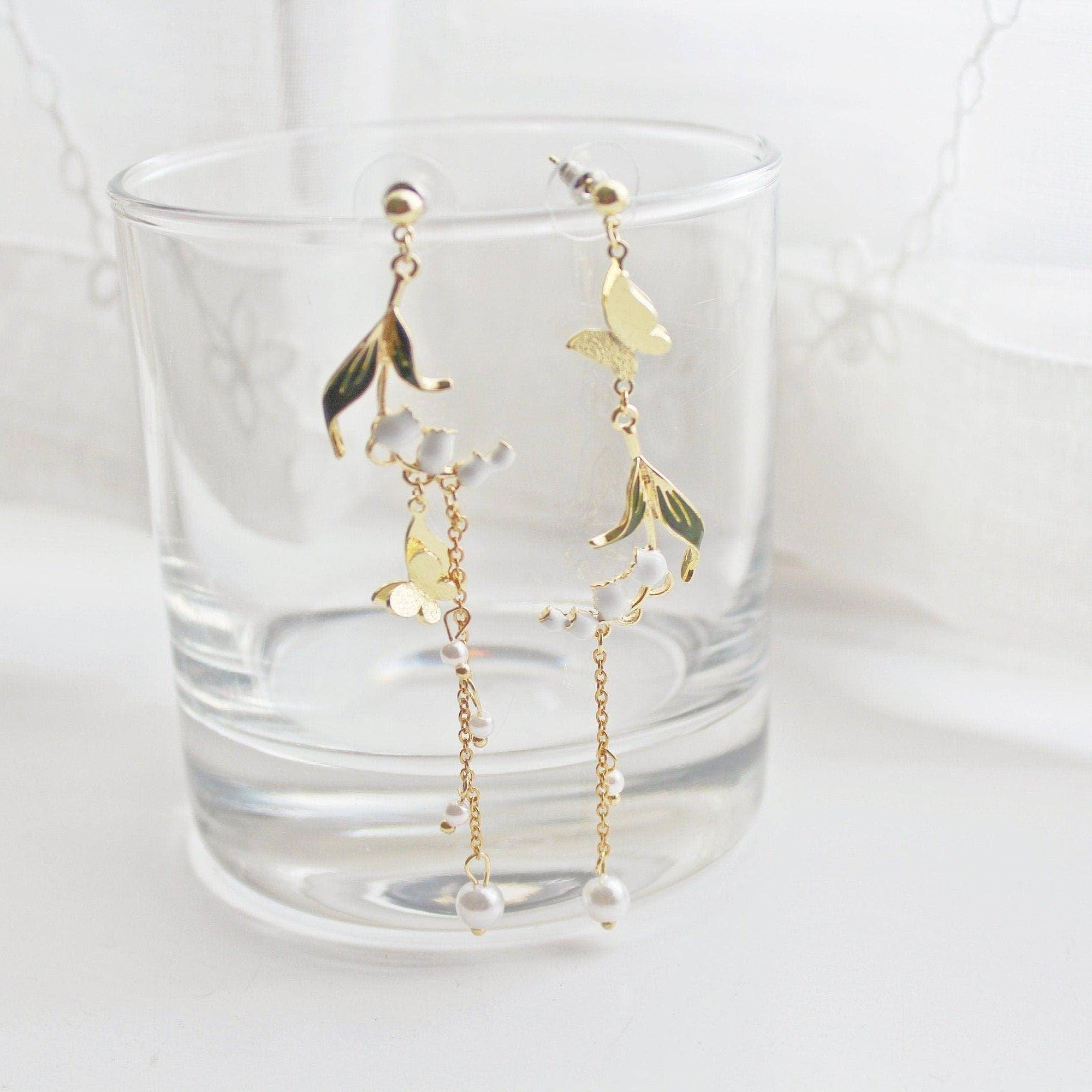 Elegant Lily of the Valley asymmetric drop earrings in gold plated bronze and sterling silver, symbolizing purity and happiness.