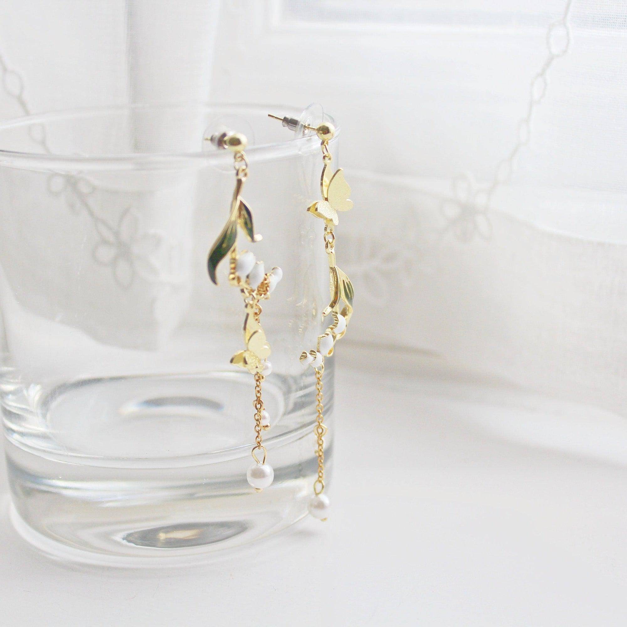 Elegant Lily of the Valley asymmetric drop earrings in gold plated bronze and sterling silver, symbolizing purity and happiness.