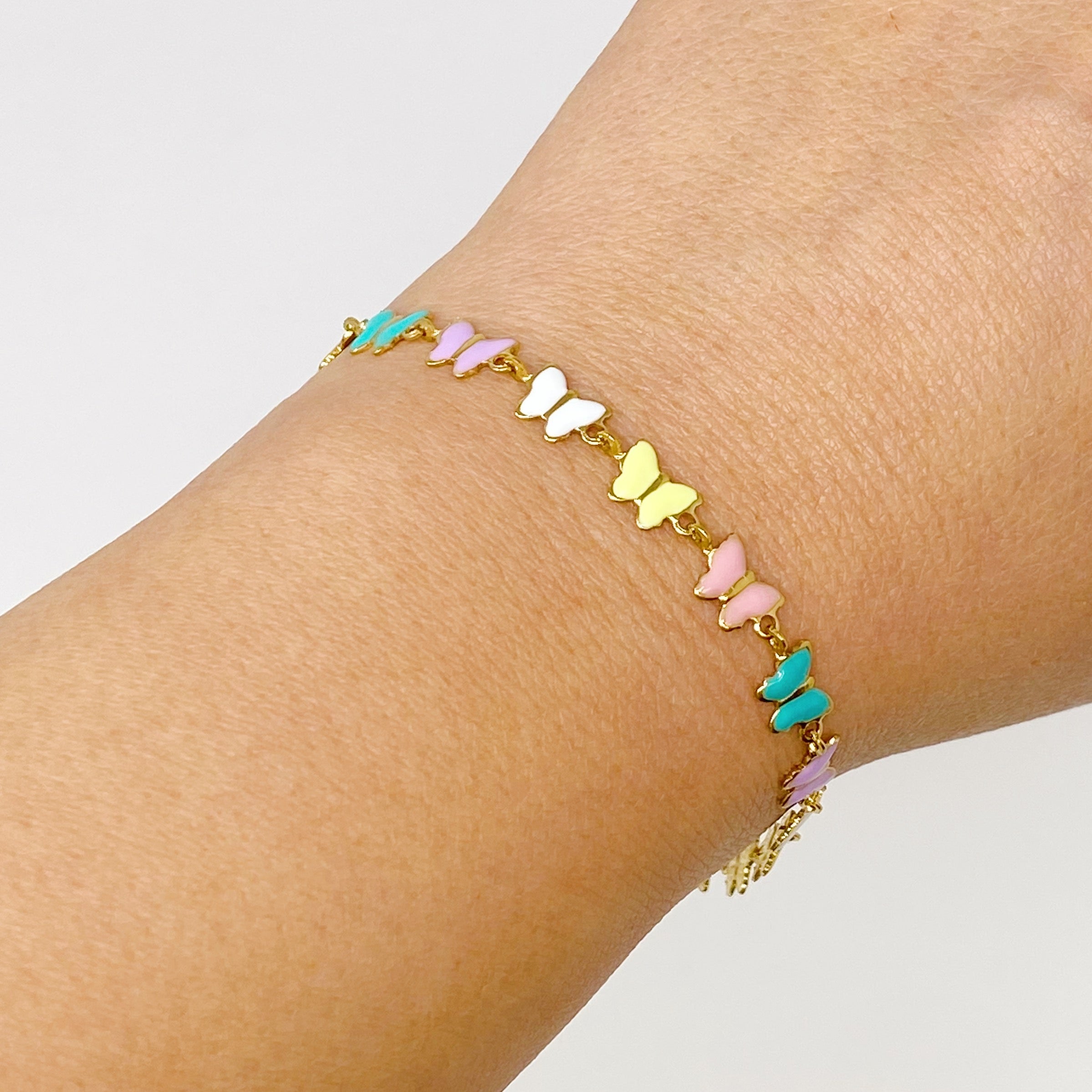 Linked Butterflies Bracelet featuring pastel butterflies and a reversible gold side, elegantly designed with intricate details.