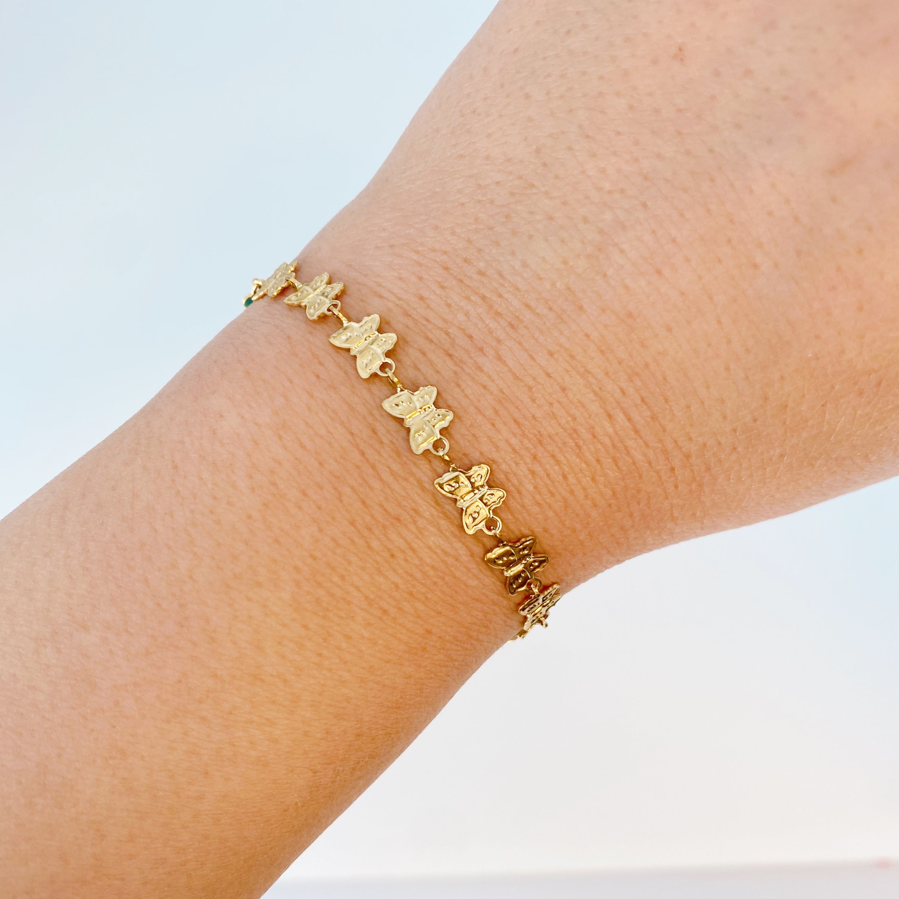 Linked Butterflies Bracelet featuring pastel butterflies and a reversible gold side, elegantly designed with intricate details.