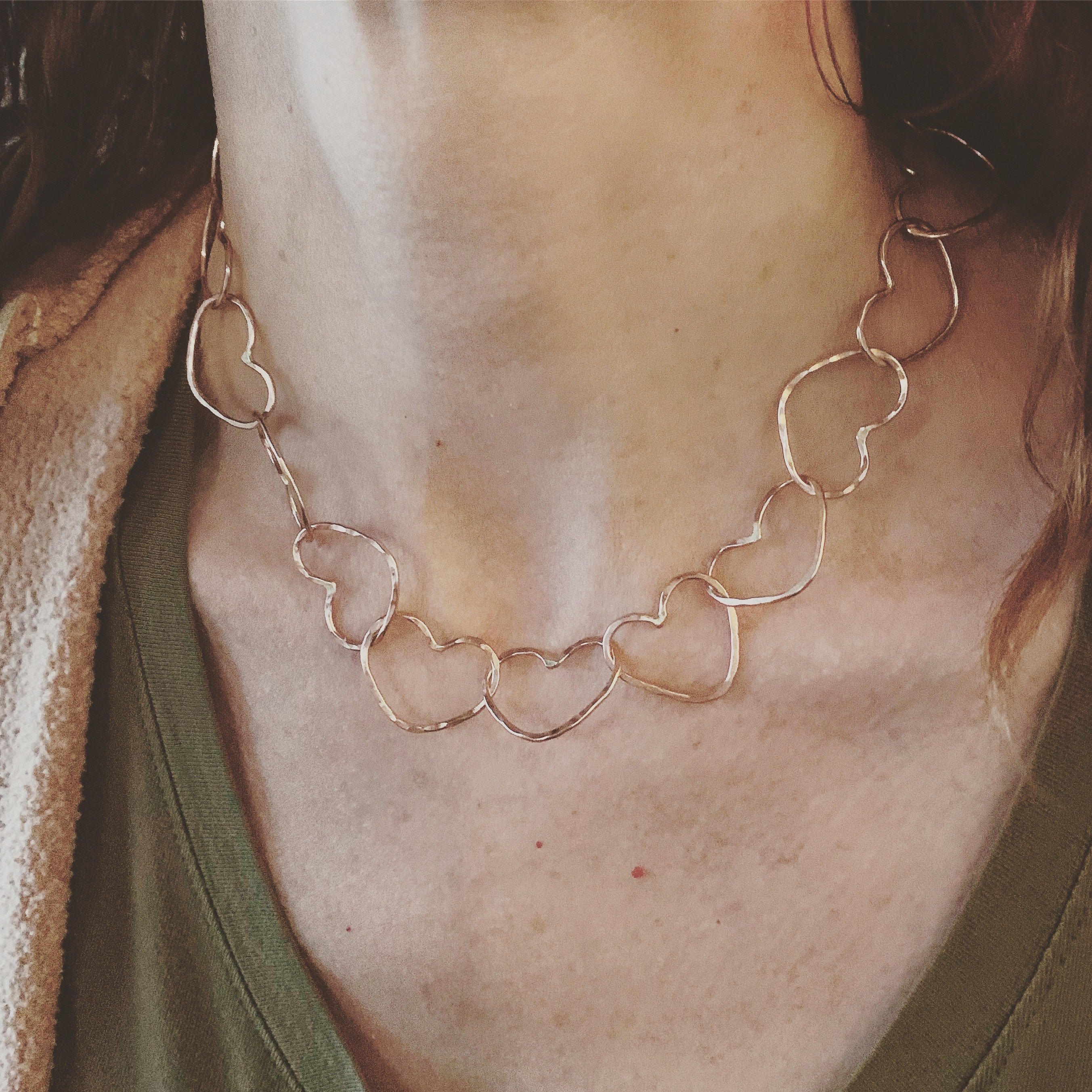 A handmade Linked Heart Chakra Necklace featuring 22 unique heart links, crafted from 14-gauge wire with a rustic finish.