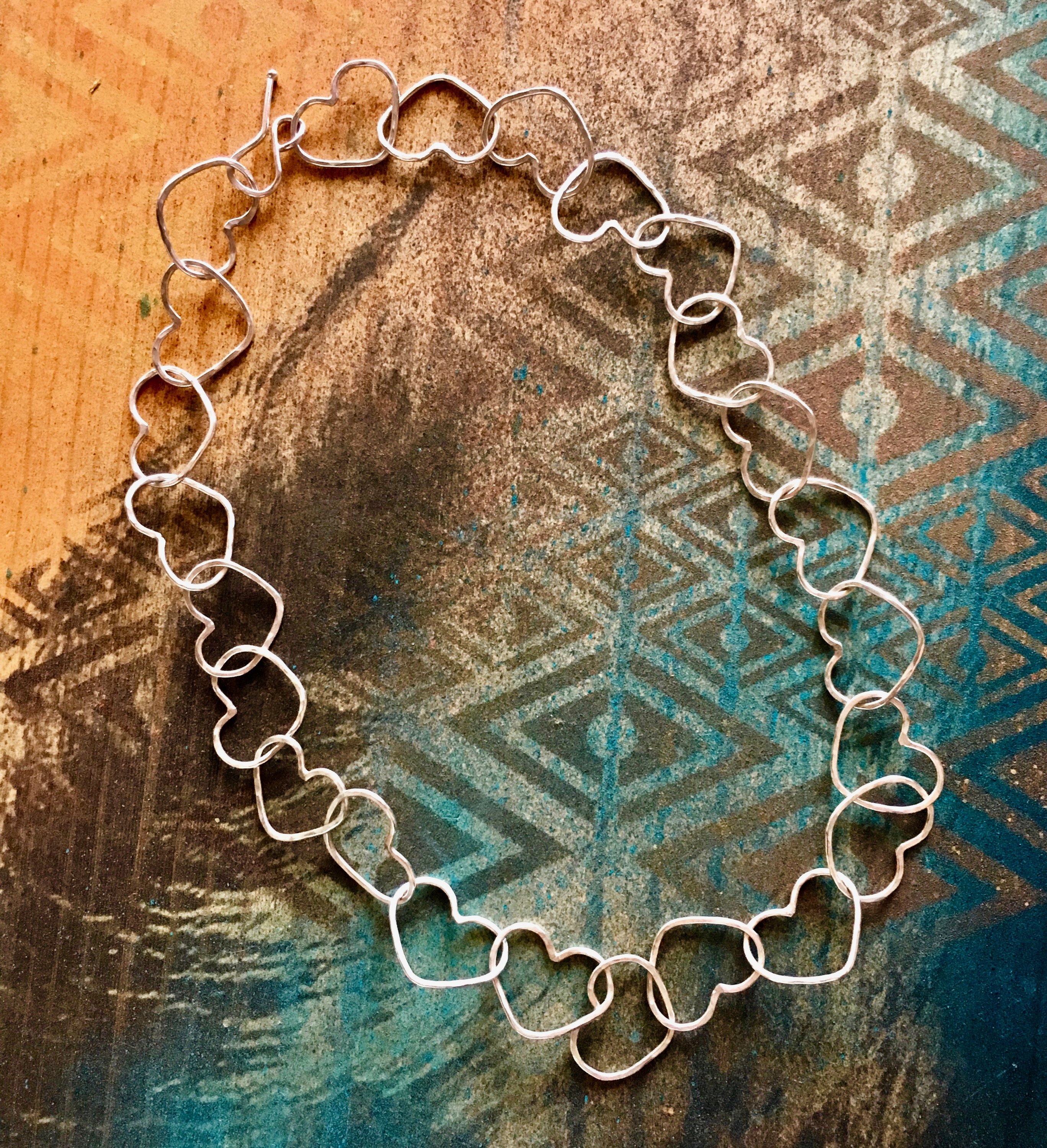 A handmade Linked Heart Chakra Necklace featuring 22 unique heart links, crafted from 14-gauge wire with a rustic finish.