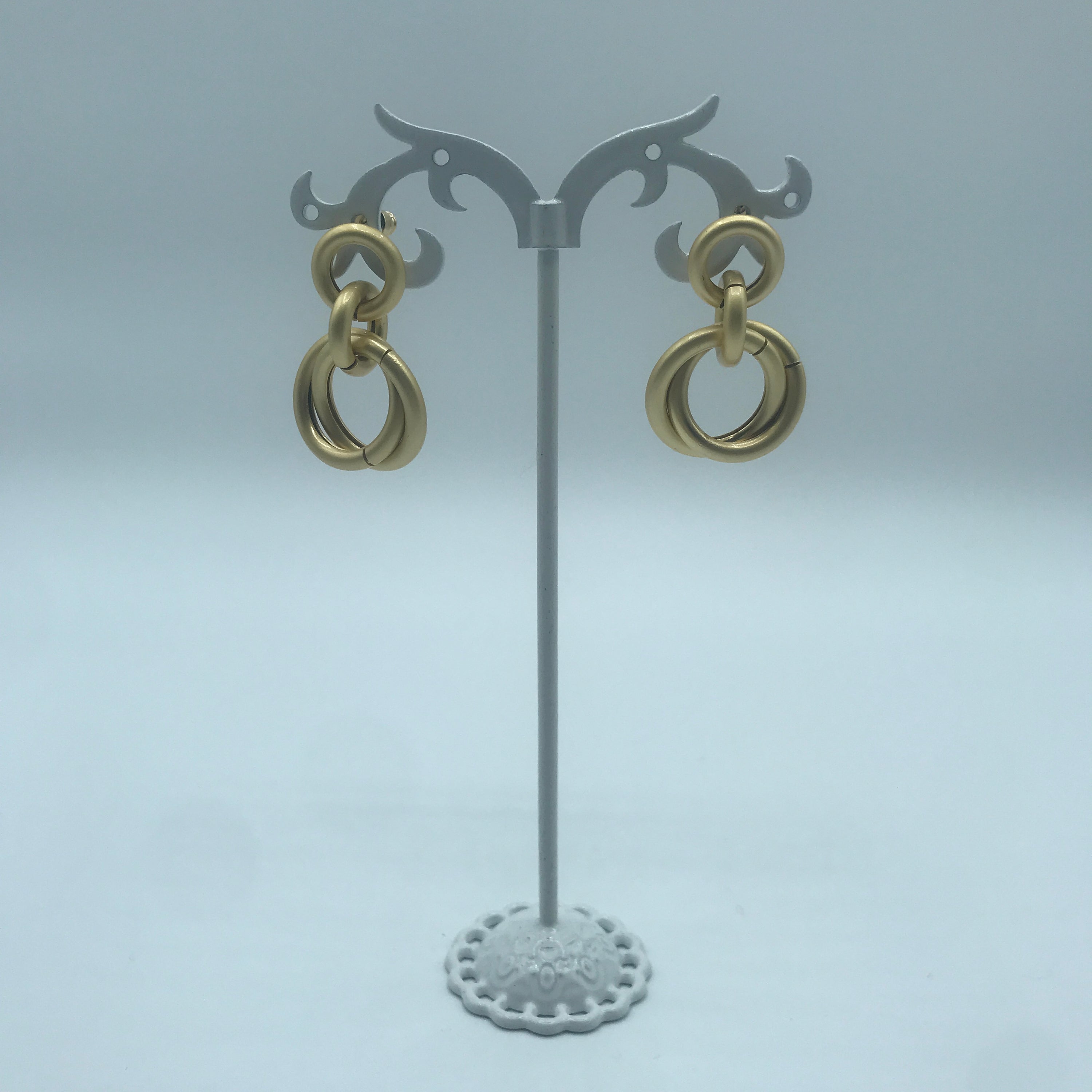 A pair of elegant linking crossed hoops earrings made from brass and s925 silver, showcasing a modern design.