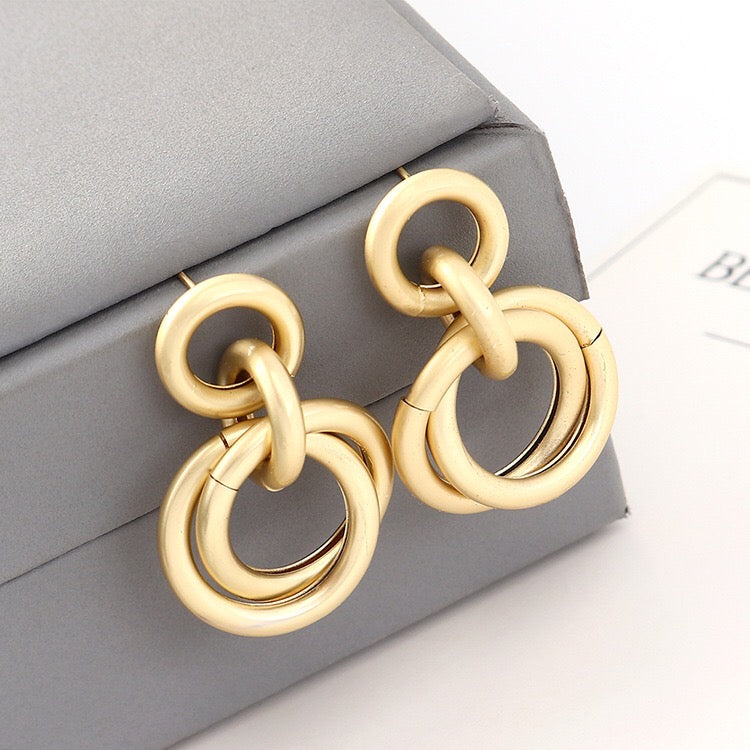 A pair of elegant linking crossed hoops earrings made from brass and s925 silver, showcasing a modern design.