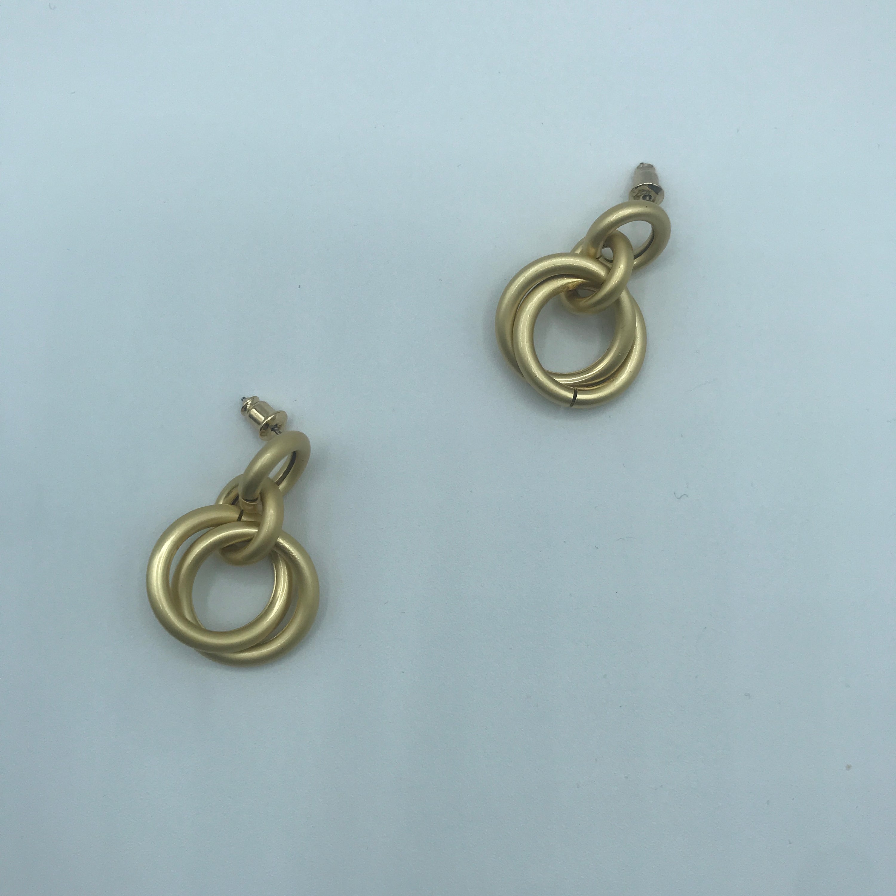 A pair of elegant linking crossed hoops earrings made from brass and s925 silver, showcasing a modern design.